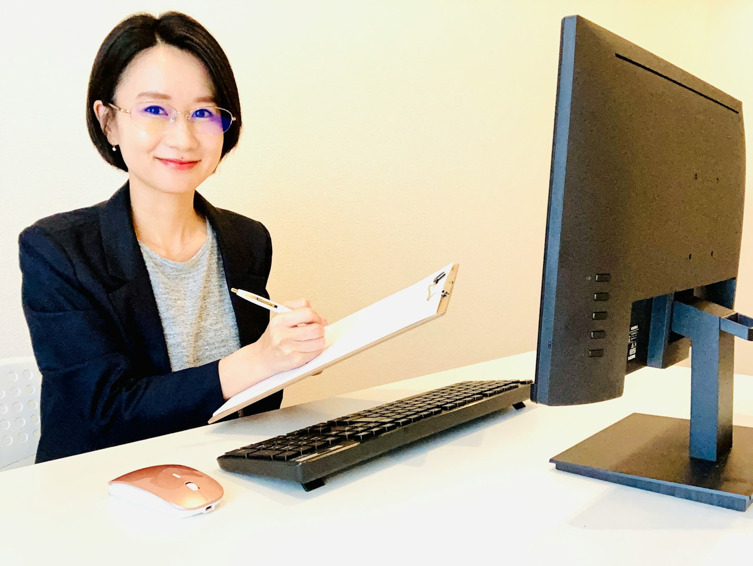 Donna che prende appunti in un ambiente d'ufficio con un computer e una tastiera sulla scrivania
