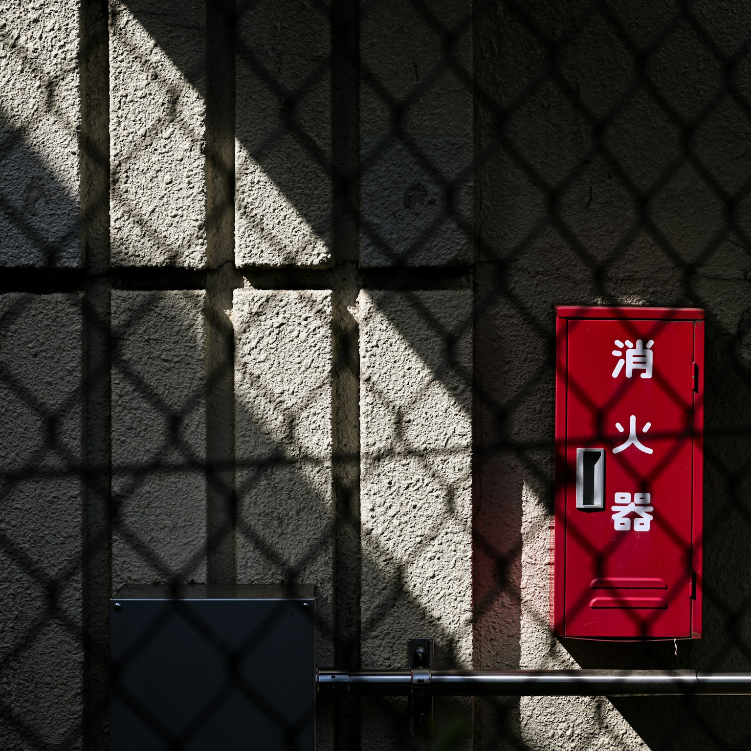Image d'un extincteur rouge sur un mur avec des ombres