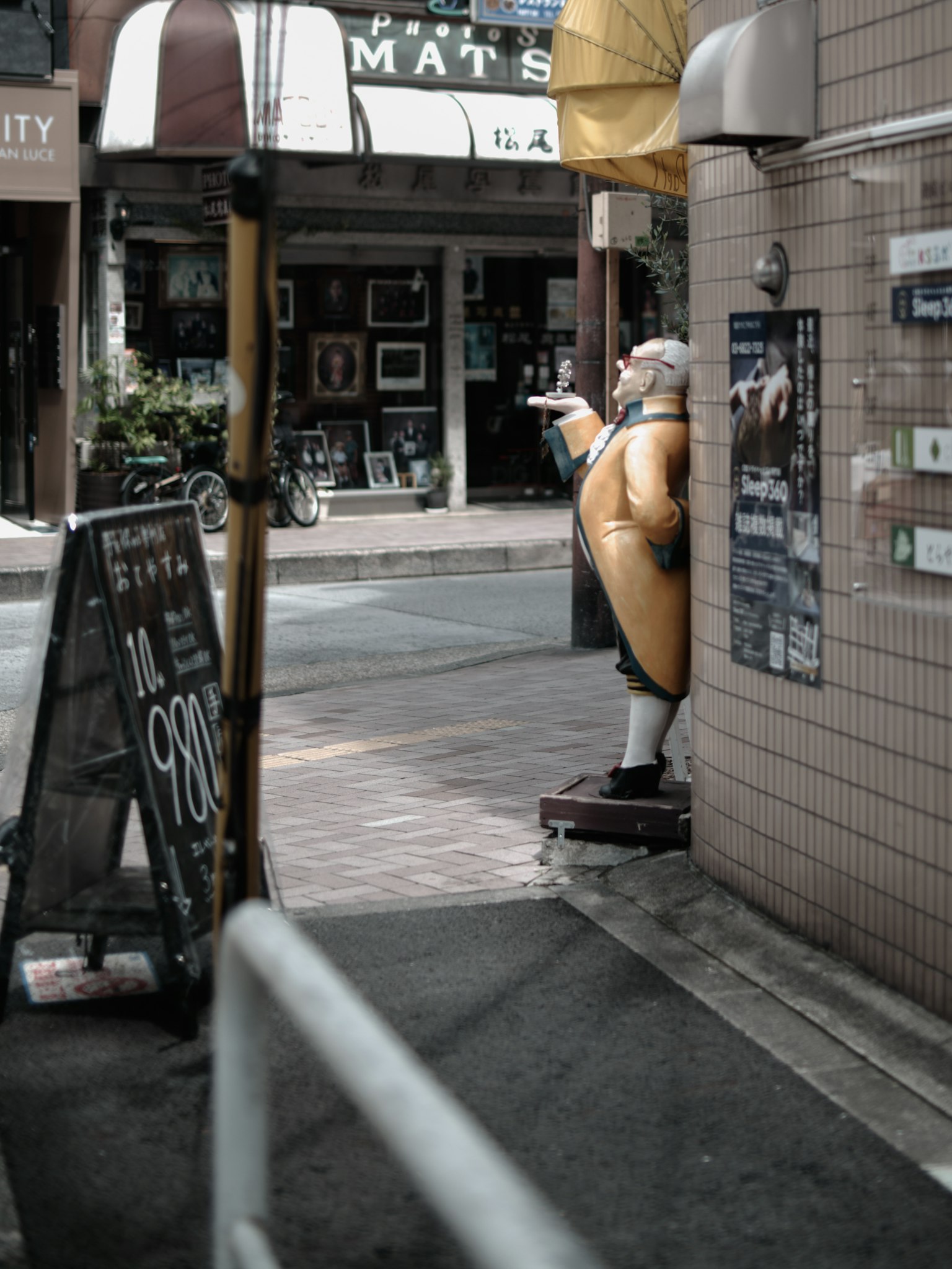 Eine gelbe Maskottchenstatue an einer Straßenecke mit einem Schild einer Kunstgalerie