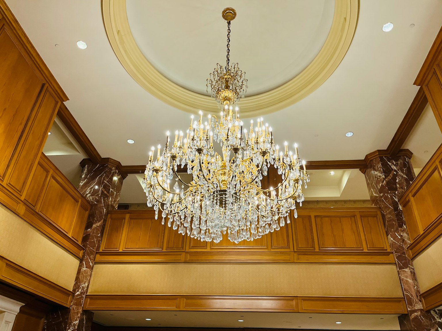 Luxurious chandelier hanging from a high ceiling in a wooden room