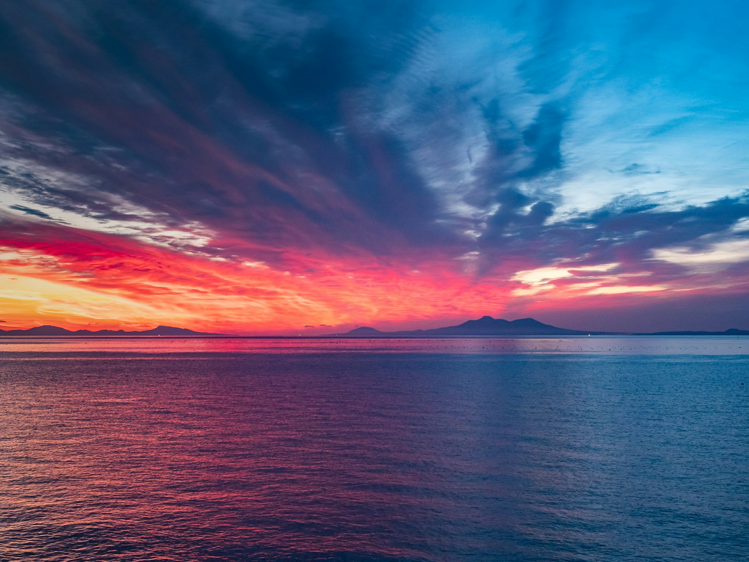 Pemandangan matahari terbenam yang indah di atas laut dengan warna-warna cerah di langit dan air