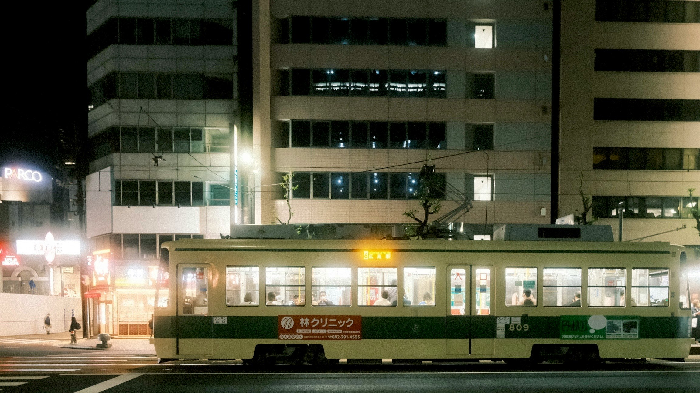 夜の街を走る電車と駅前の明かり