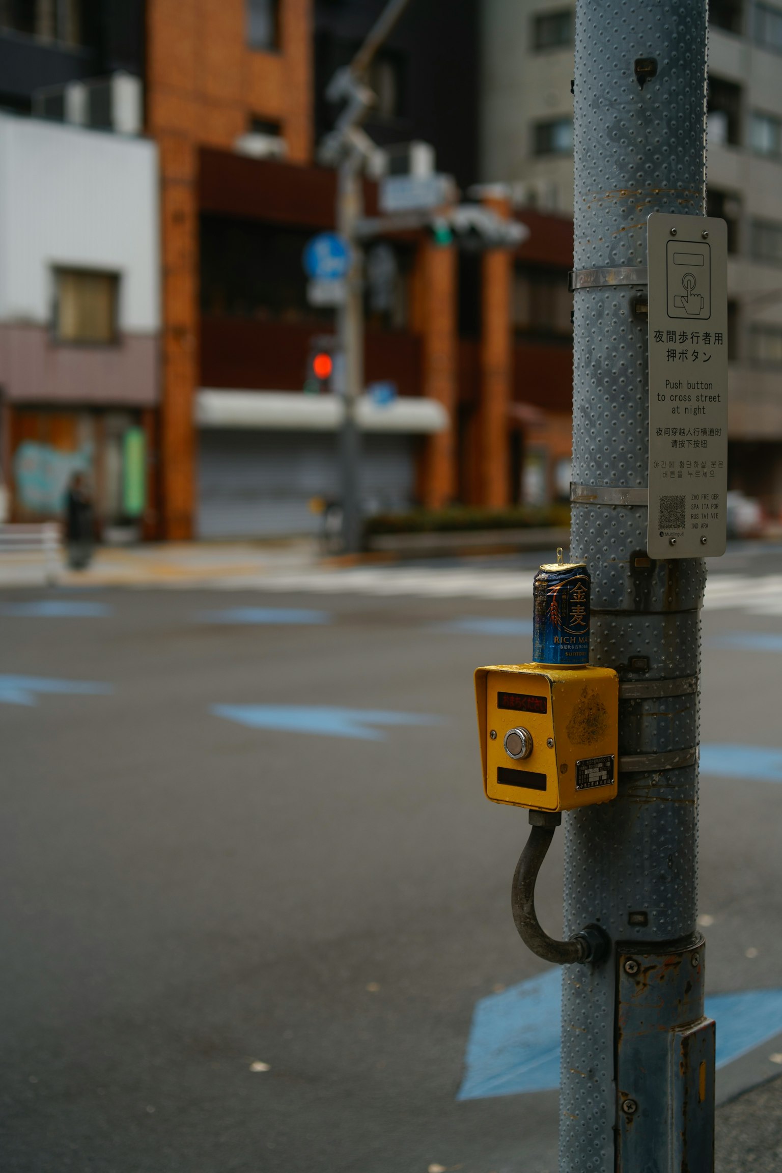 Gelber Fußgängersignalknopf in der Nähe einer Kreuzung mit Stadtgebäuden