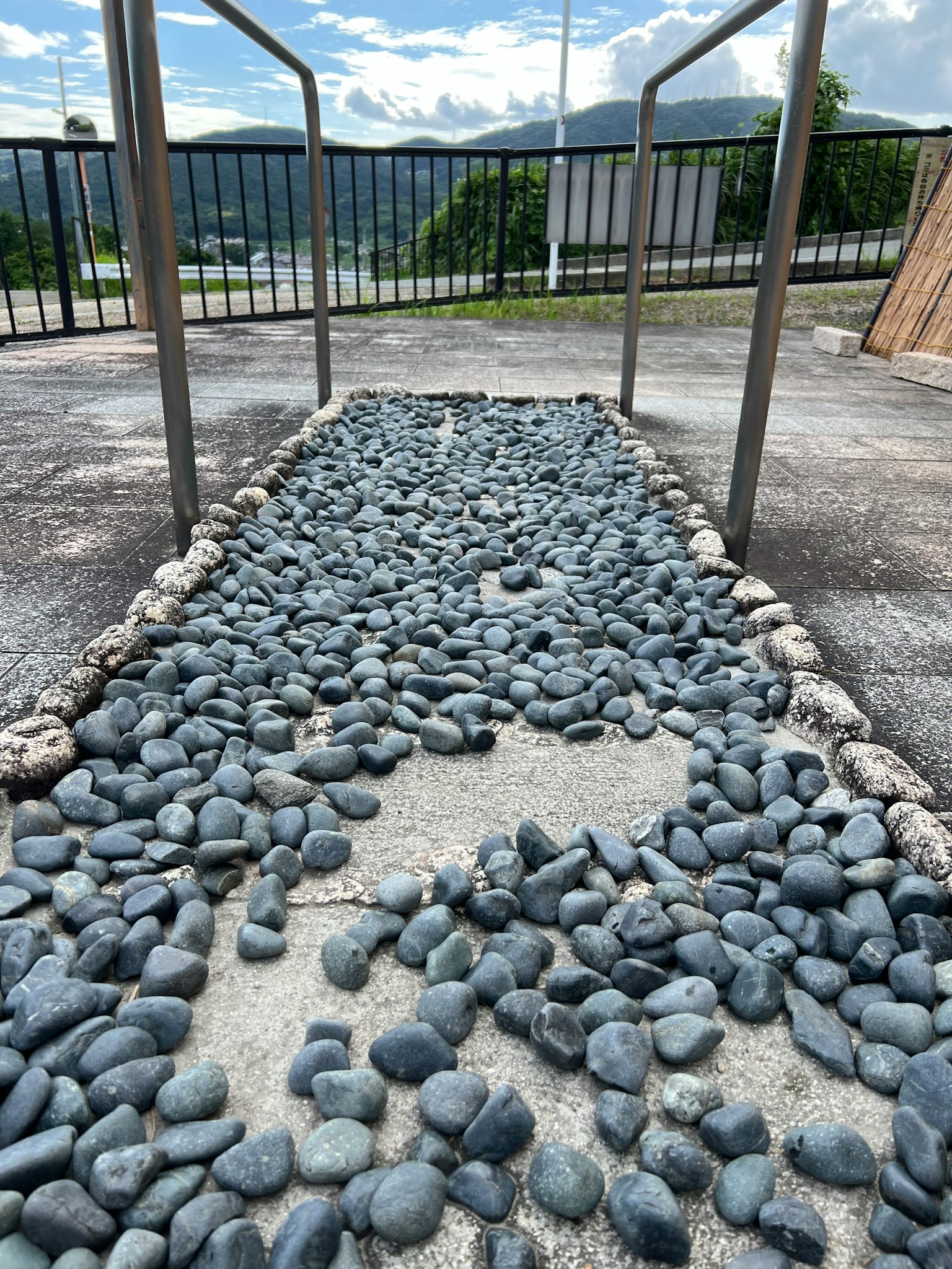 Weg mit grauen Steinen flankiert von Metallgeländern