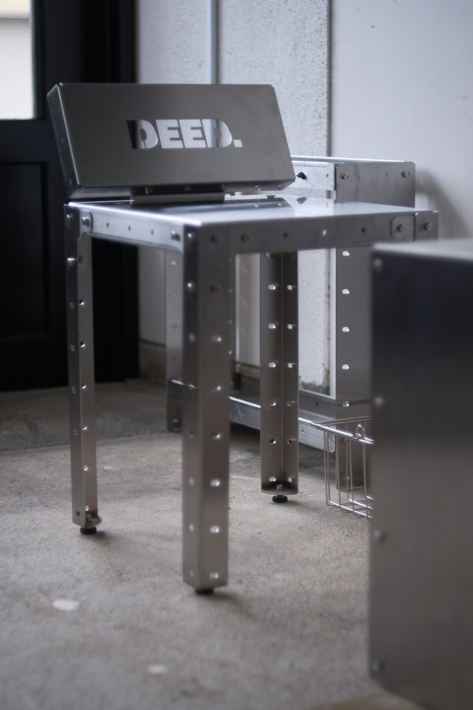 A metal chair placed in a room with the word 'DEEL' engraved on the backrest
