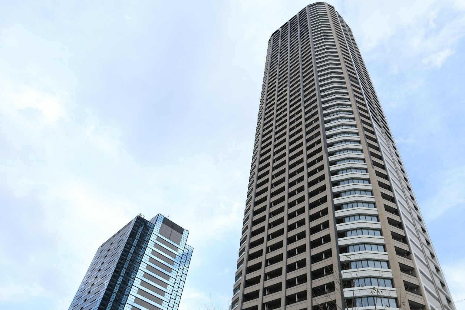 Foto di grattacieli con cielo blu che mostra un edificio alto e un edificio più corto in primo piano