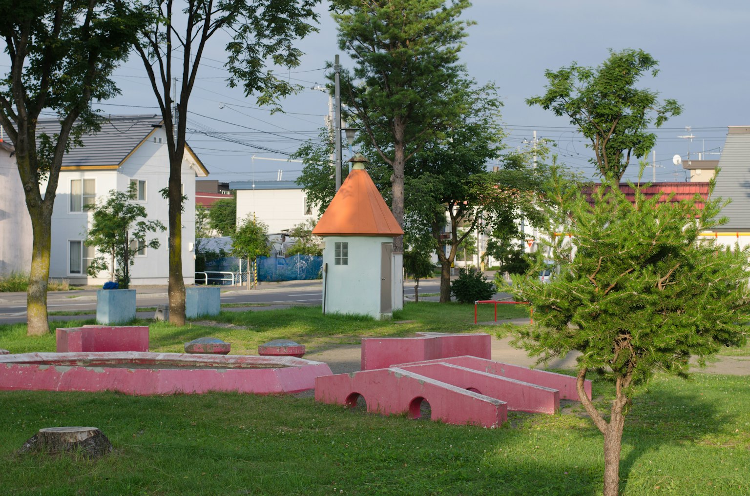 Une scène de parc avec des structures de jeu colorées et un petit bâtiment