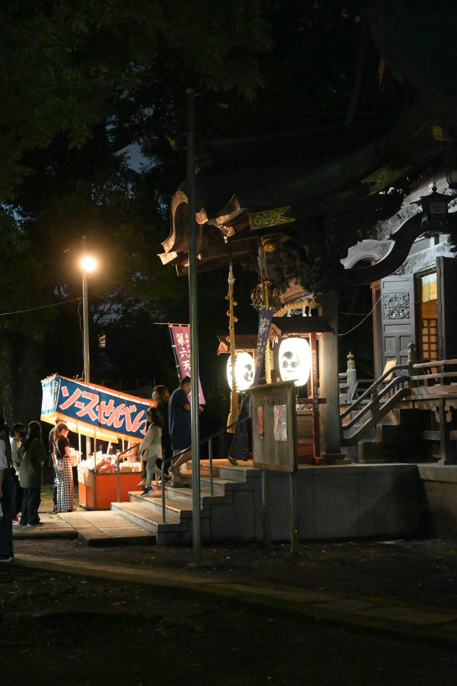 Pintu masuk kuil di malam hari dengan orang dan lentera