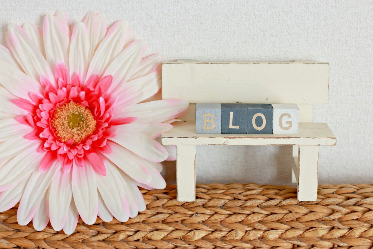 Un banco blanco con la palabra BLOG y una flor rosa grande