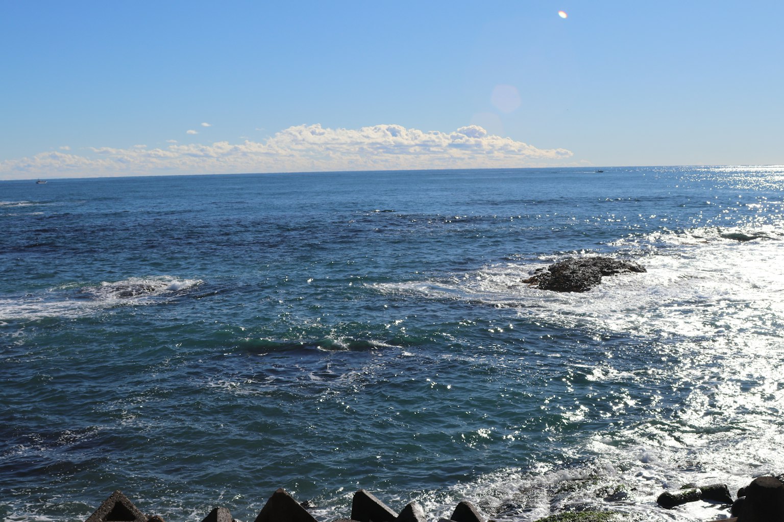 Océan bleu avec des nuages blancs et une plage rocheuse