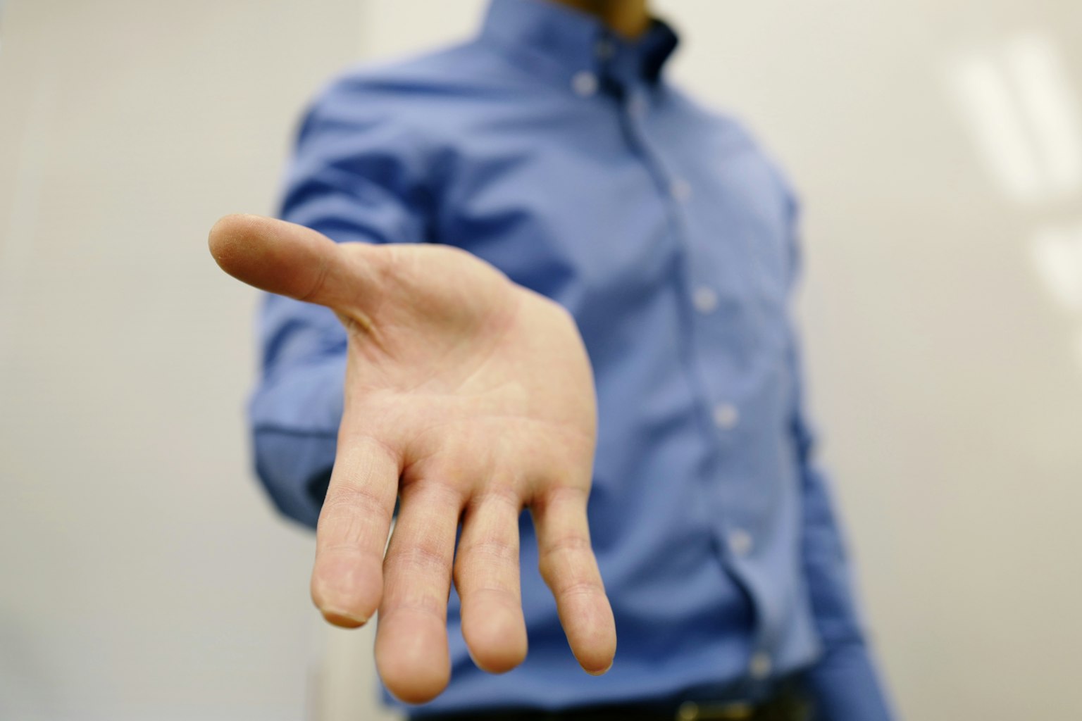 La mano de un hombre está extendida usando una camisa azul