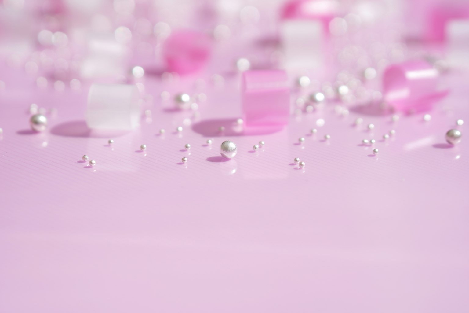 Display of transparent pink and white blocks with small pearls on a soft pink background