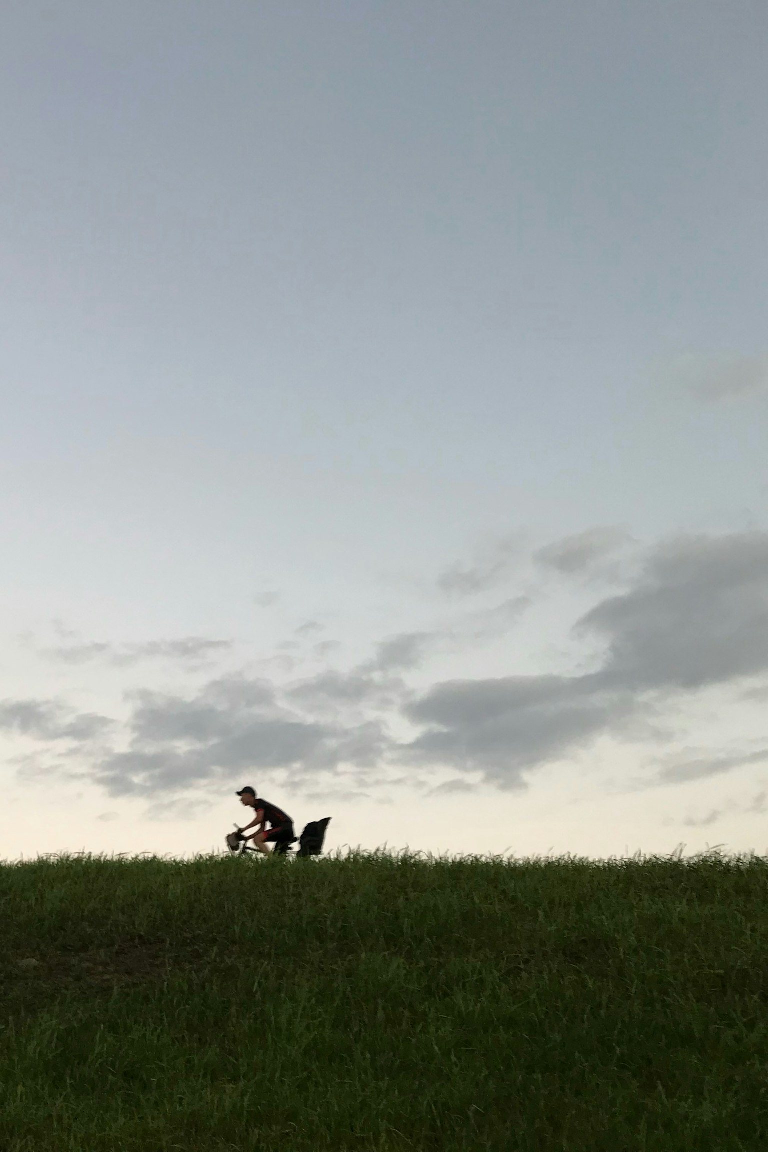 Silhouette d'une personne assise sur une colline avec un ciel vaste