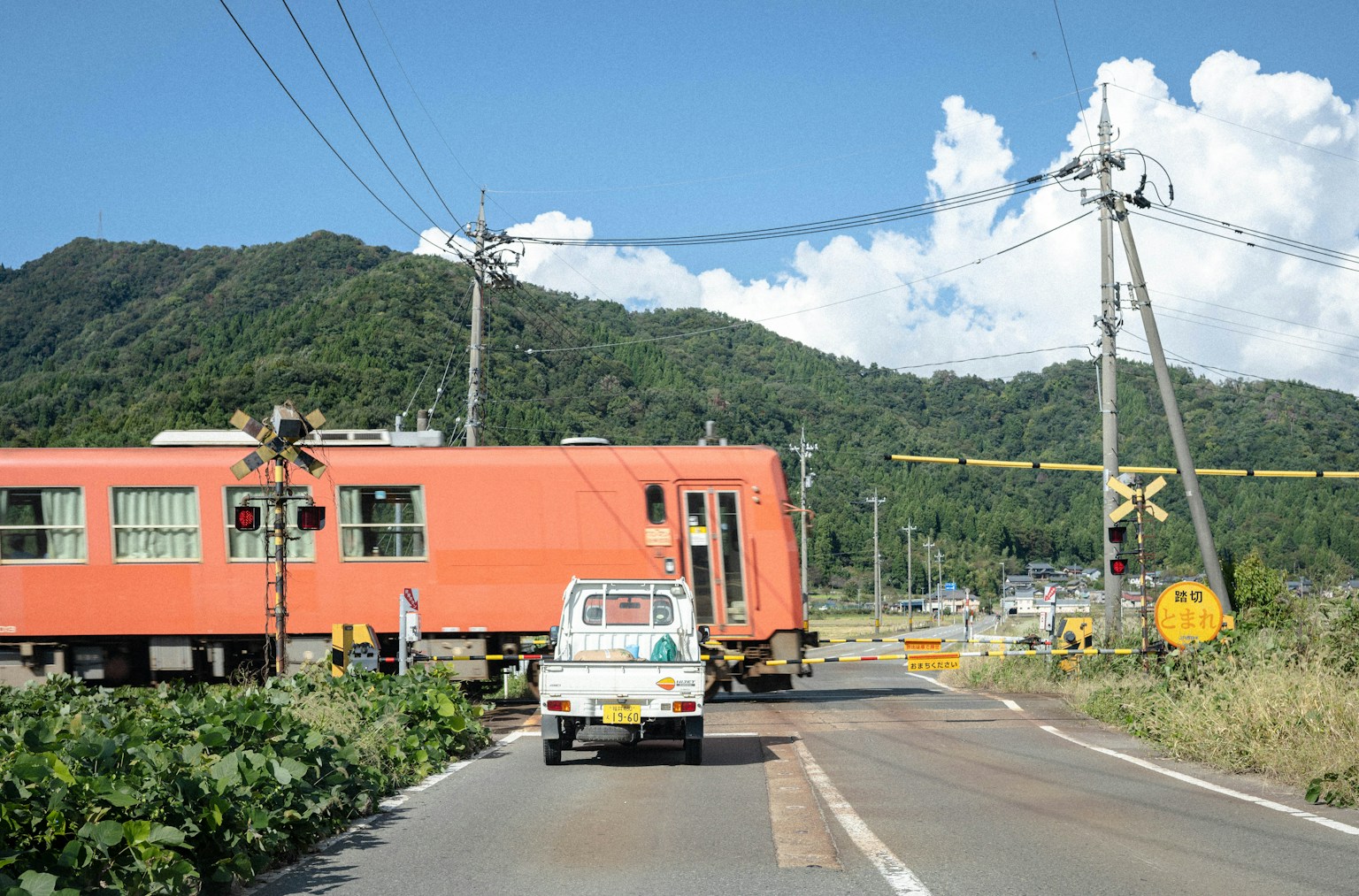 Rural intersection with an orange train passing by