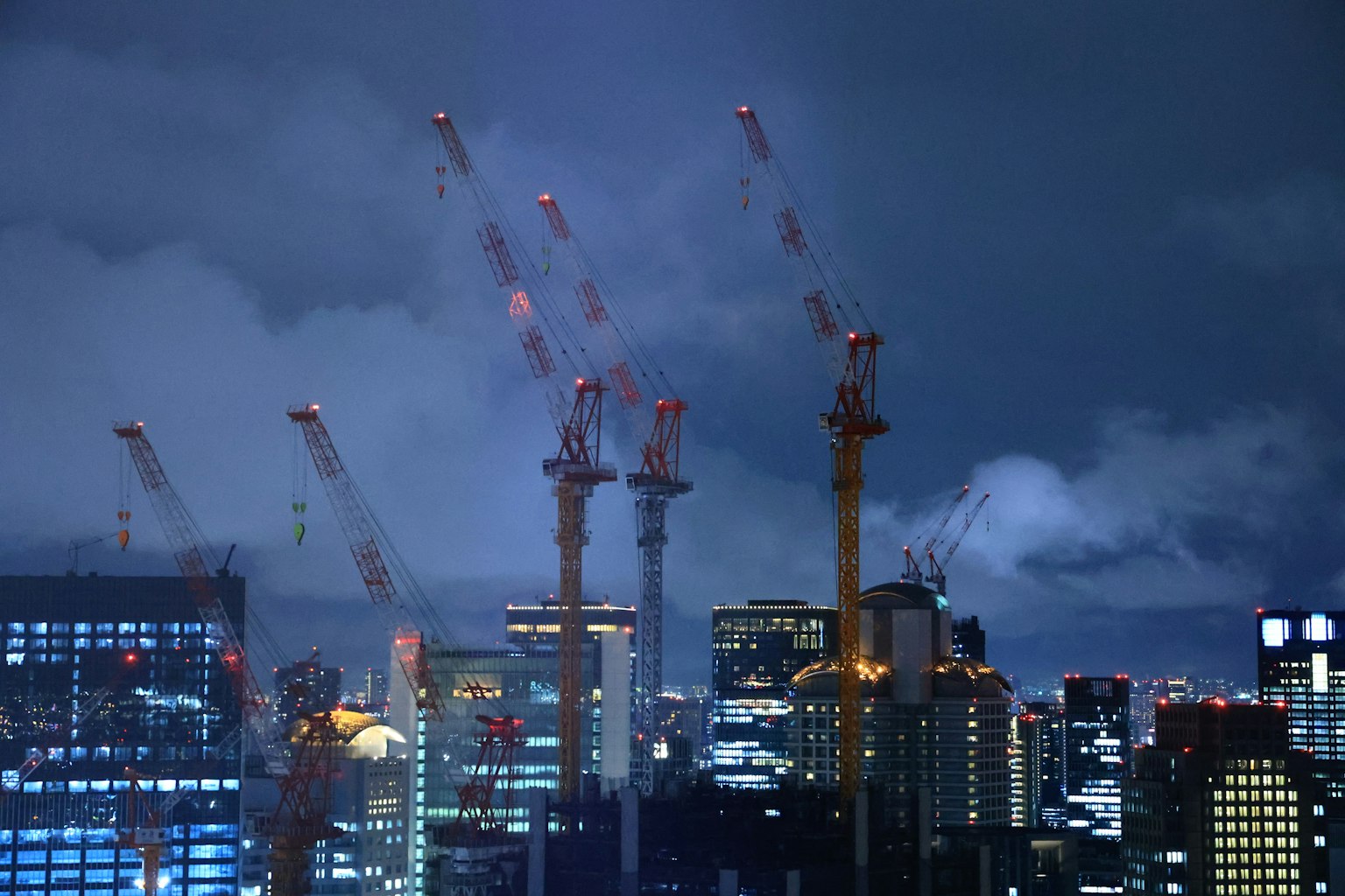 夜间城市景观中起重机和摩天大楼的轮廓