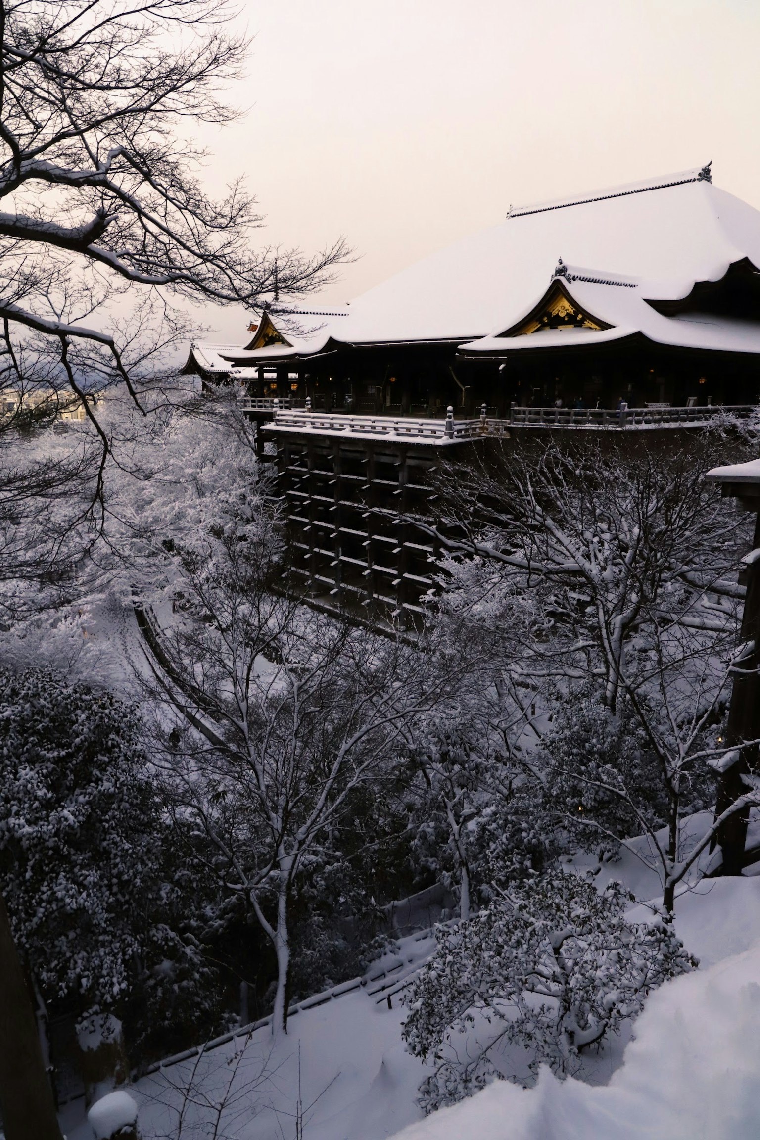 Traditionelles japanisches Gebäude, das mit Schnee bedeckt ist, umgeben von Bäumen