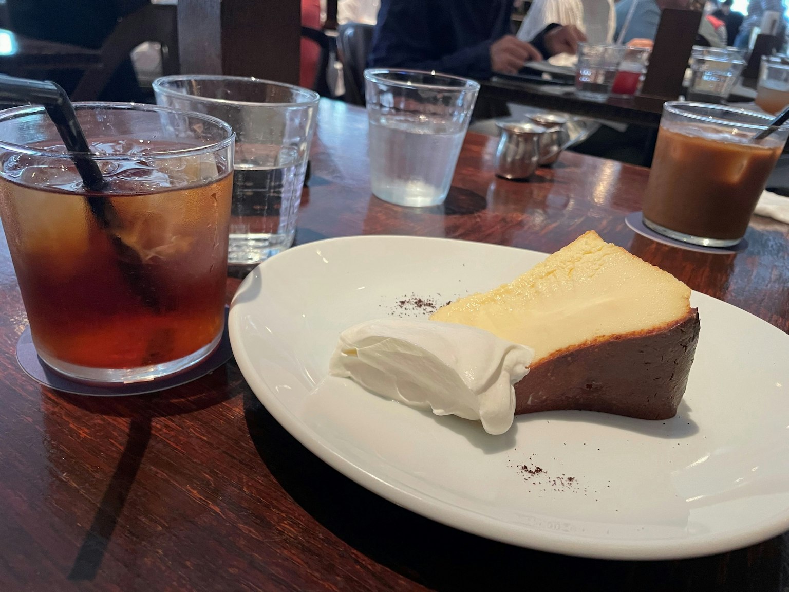 一片起司蛋糕和一杯冰茶放在木桌上