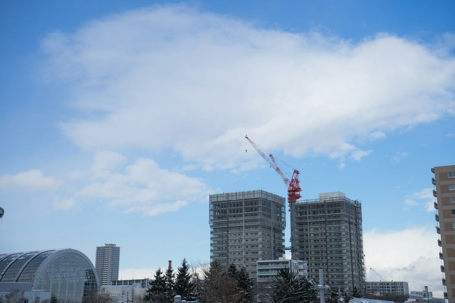 藍天下兩棟高樓和一台起重機的景觀
