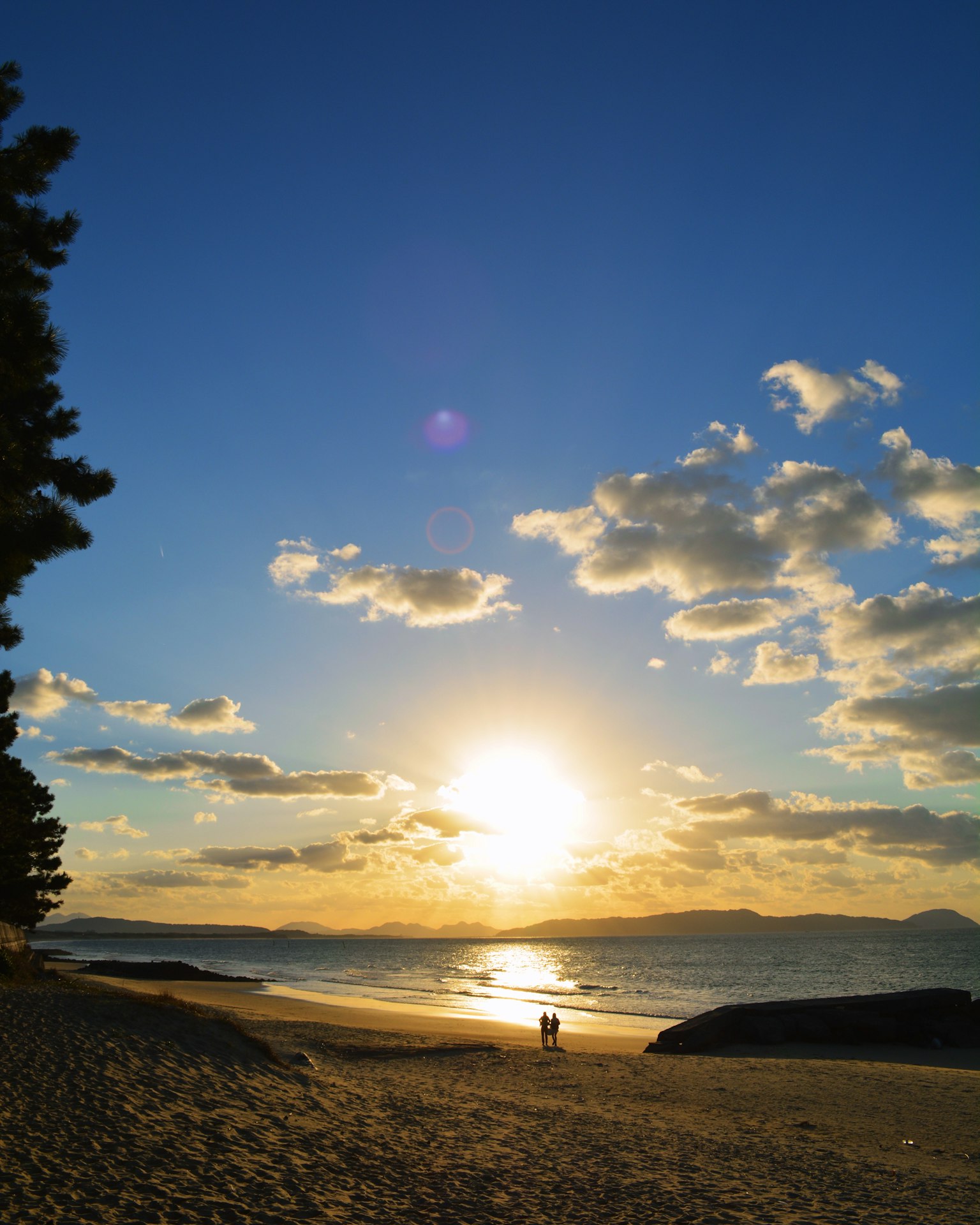 Beautiful beach sunset scene blue sky white clouds sunlight reflecting on the sea