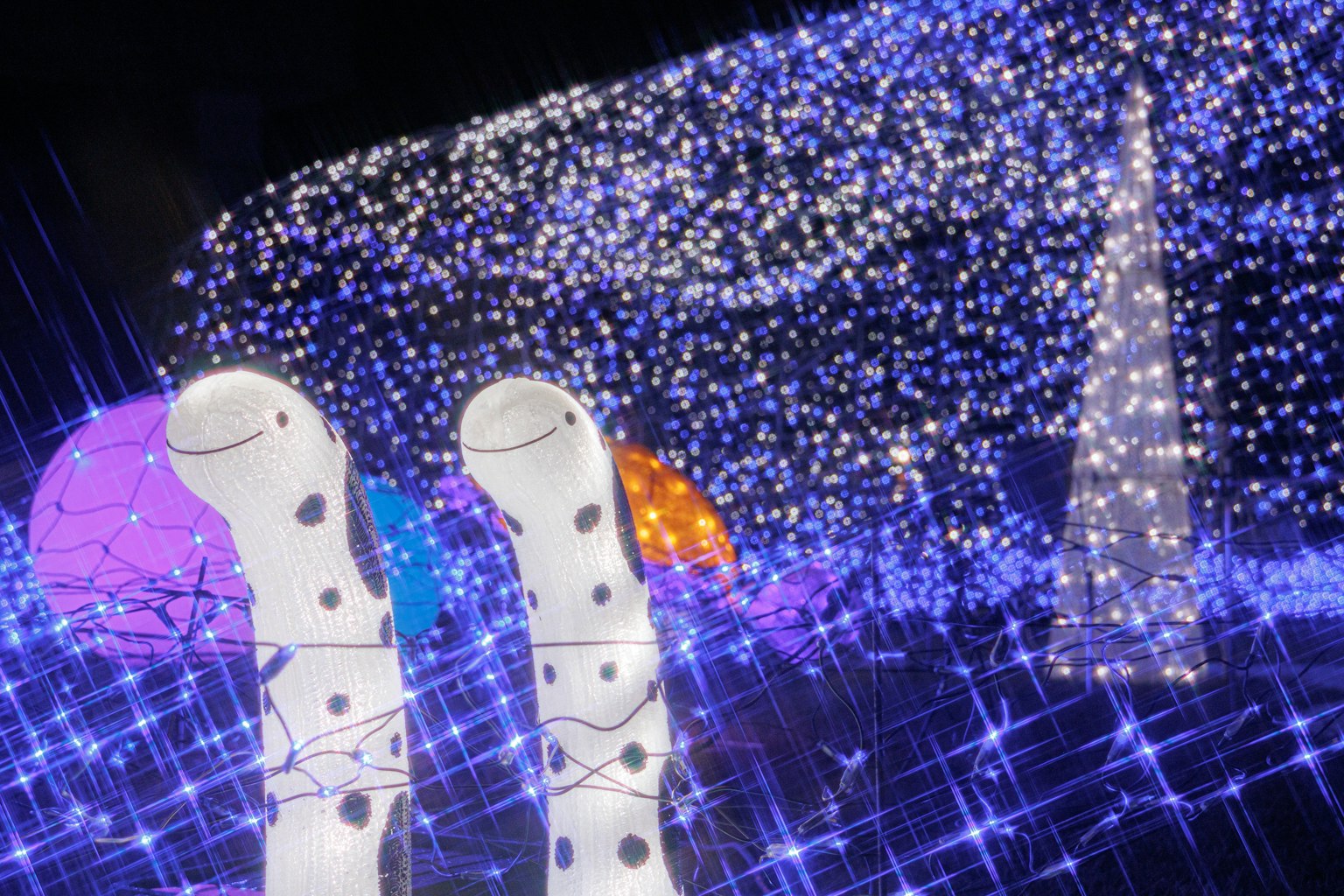 Weiße Stiefel mit schwarzen Punkten im Vordergrund vor einem bunten, beleuchteten Hintergrund mit blauen und lila Lichtern