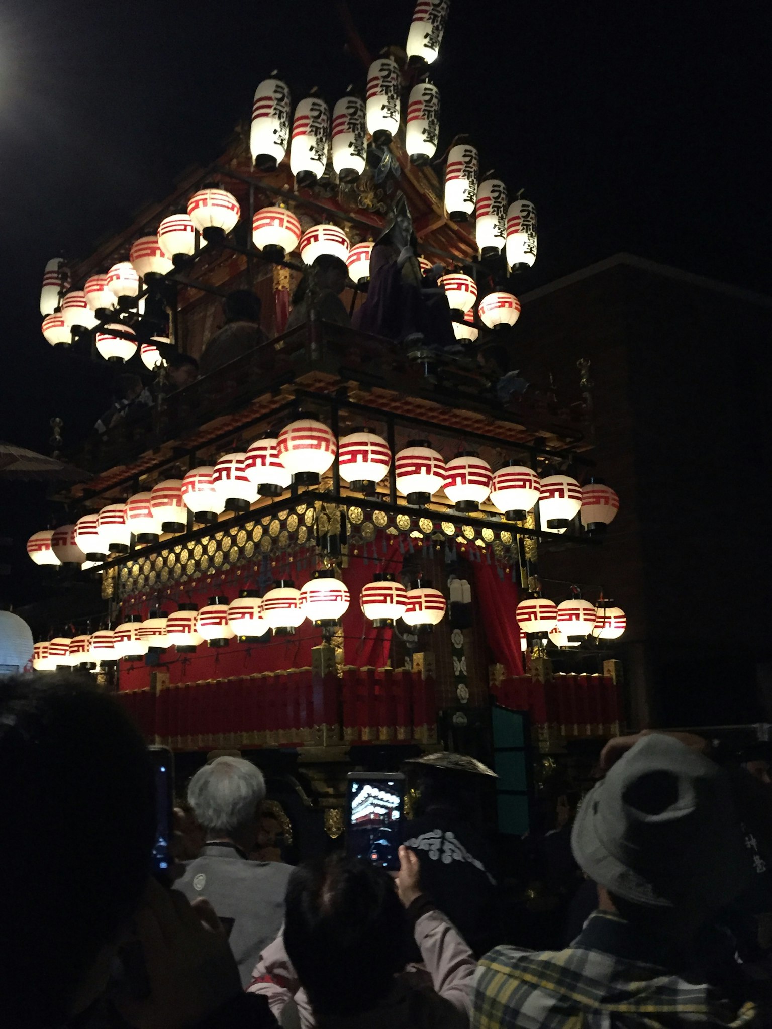 Festival float adorned with lanterns at night with spectators