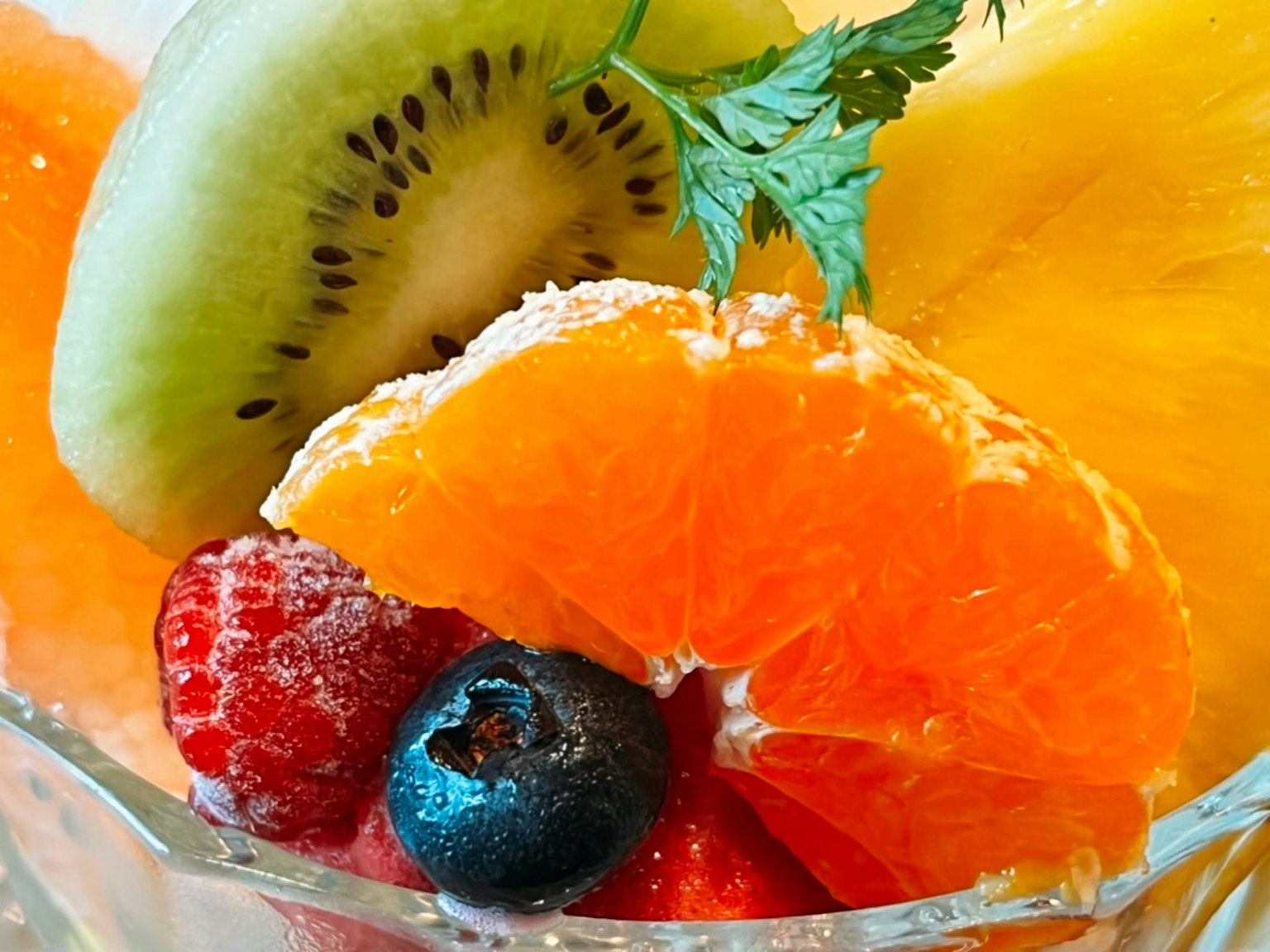Tazón de ensalada de frutas colorido con kiwi, naranja, piña, frambuesa y arándano