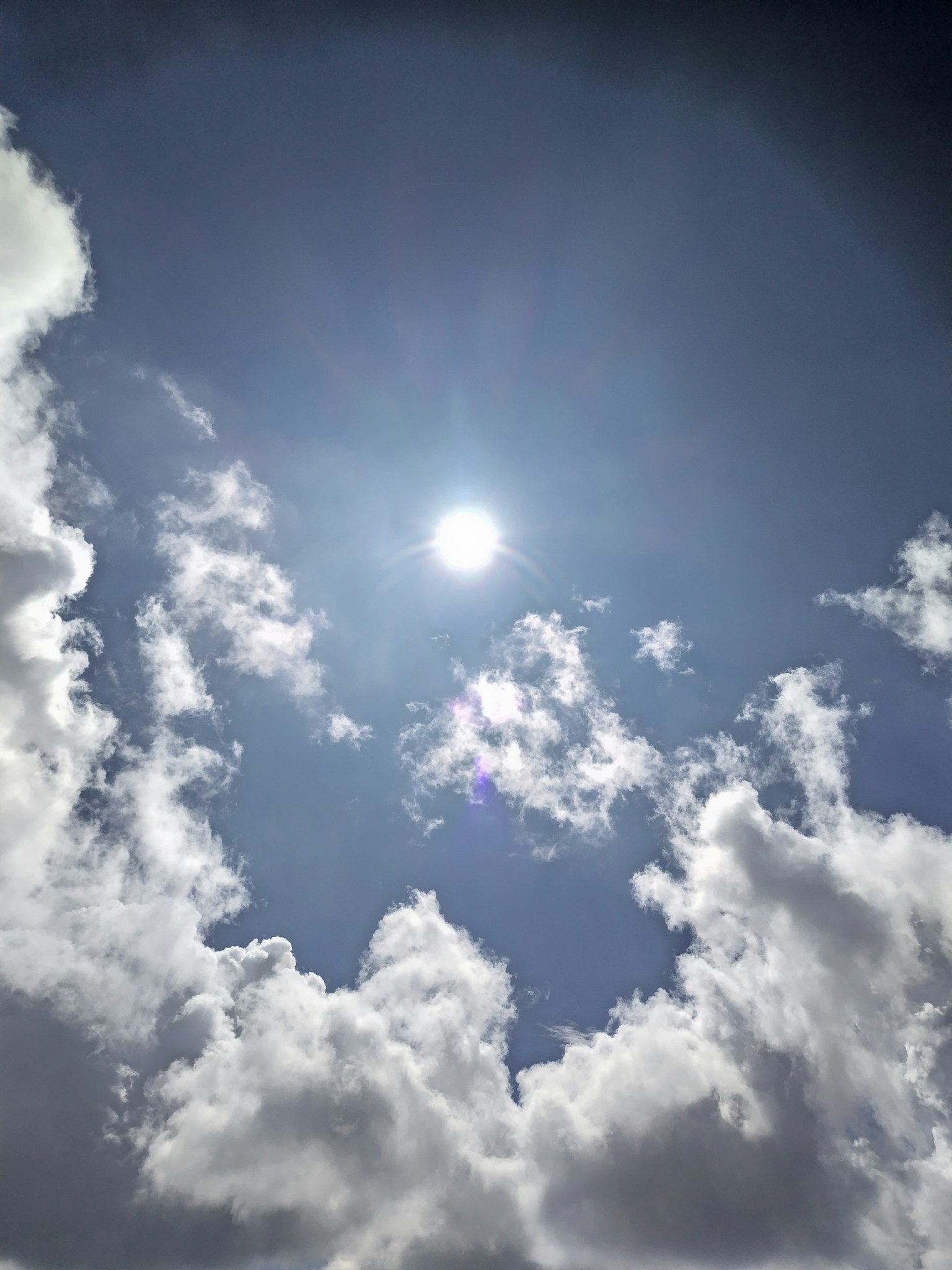 Helle Sonne scheint in einem klaren blauen Himmel mit flauschigen weißen Wolken