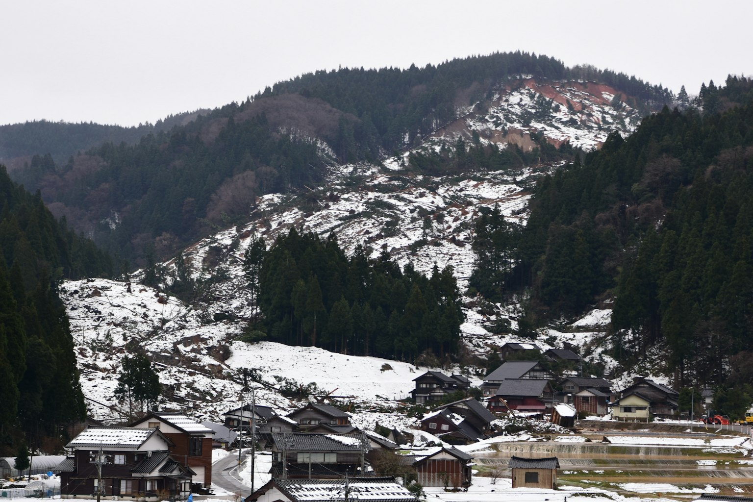 Paesaggio di un villaggio di montagna innevato con foreste verdi