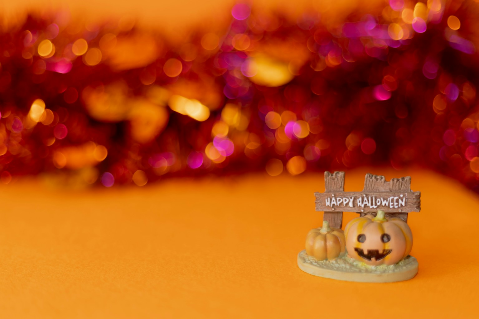 Dekorasi Halloween kecil dengan labu tersenyum dan papan bertuliskan Selamat Halloween di latar belakang oranye