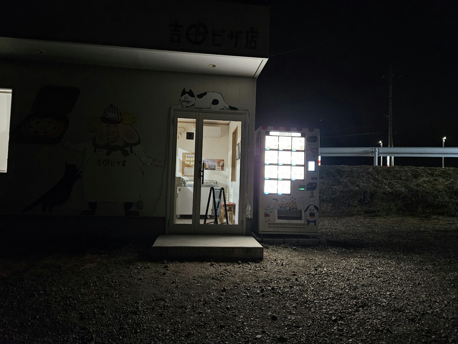 Exterior de un pequeño edificio iluminado por la noche con luz que sale de las ventanas y oscuridad circundante