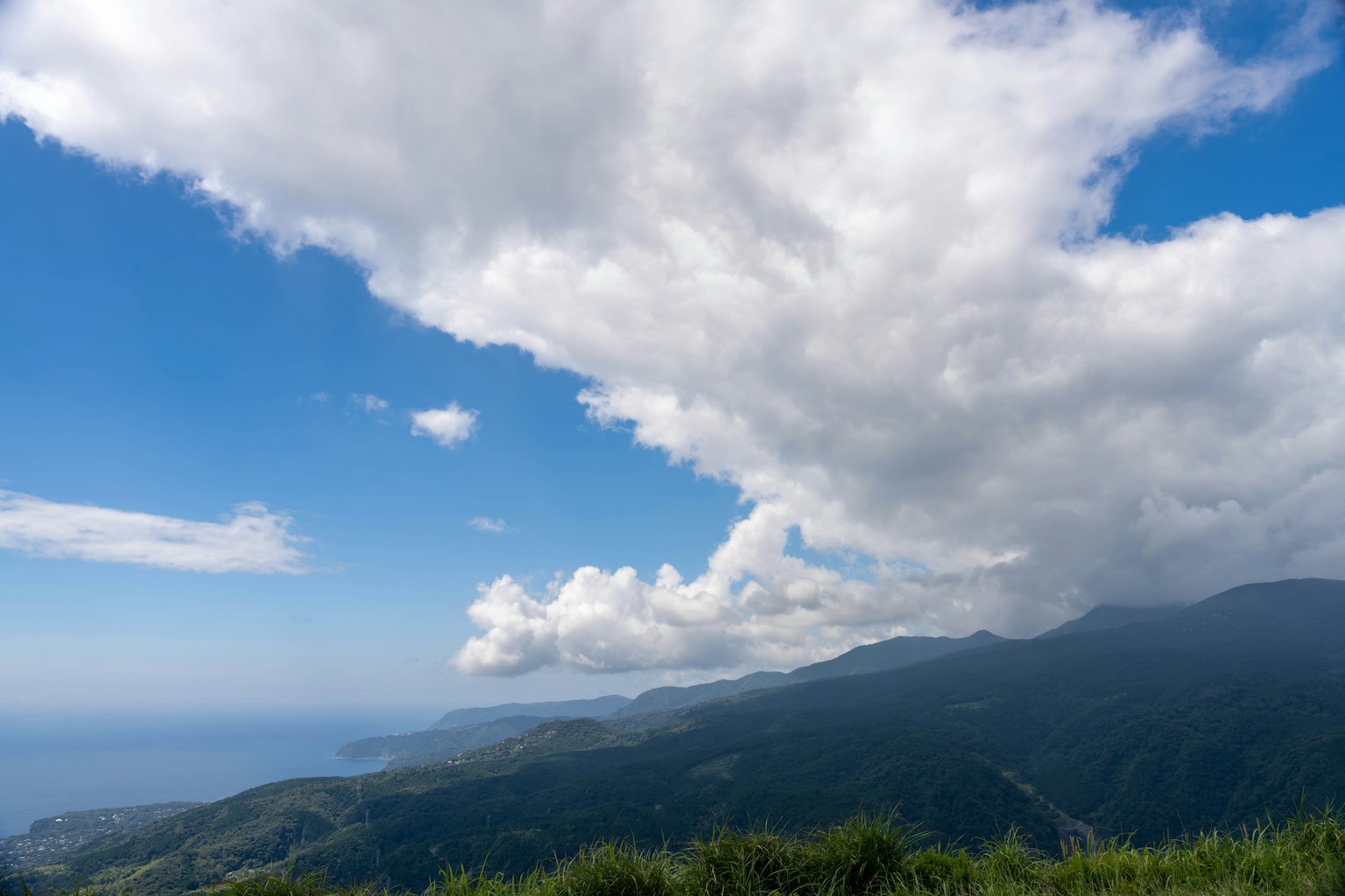 Vue panoramique d'un ciel bleu avec des nuages blancs sur des montagnes et l'océan