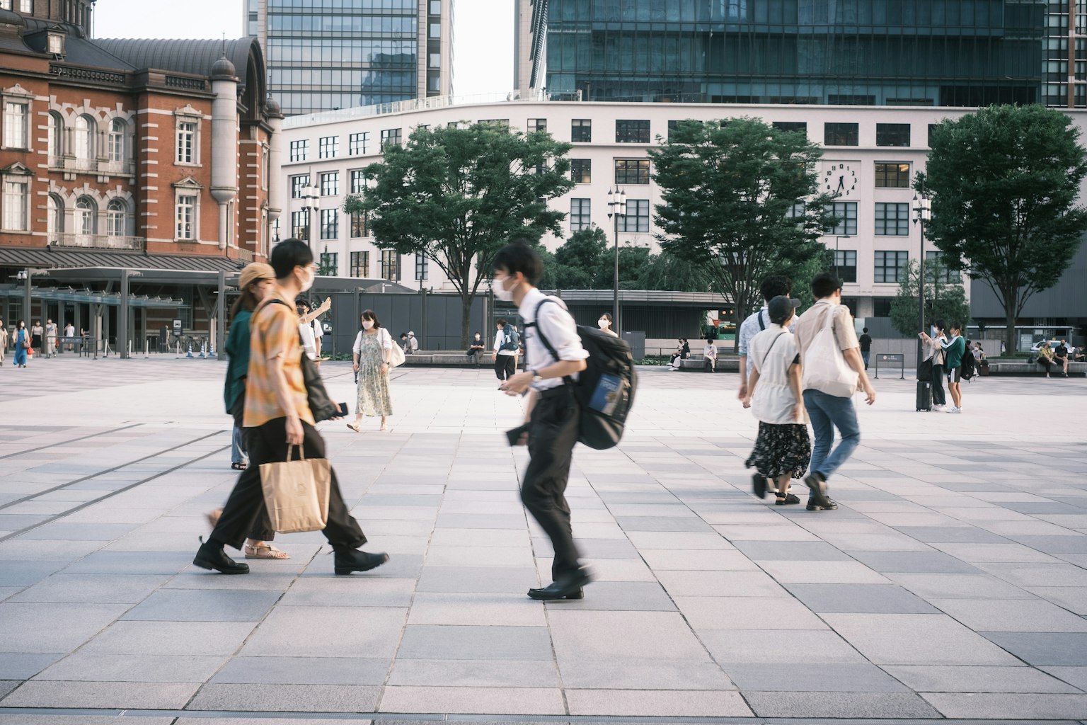 People walking in an urban square with modern buildings in the background