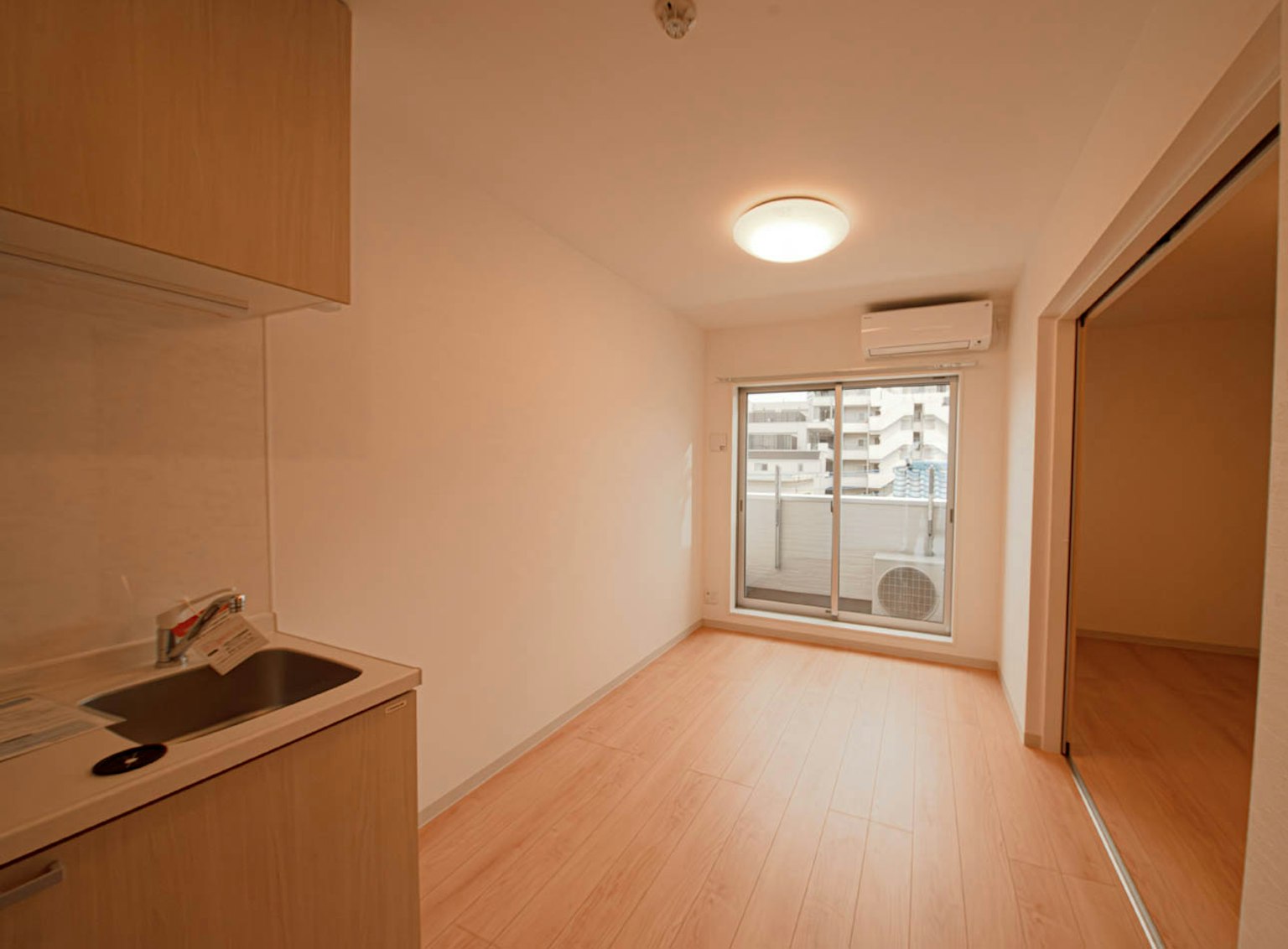 Interior de un estudio moderno y simple con área de cocina y gran ventana