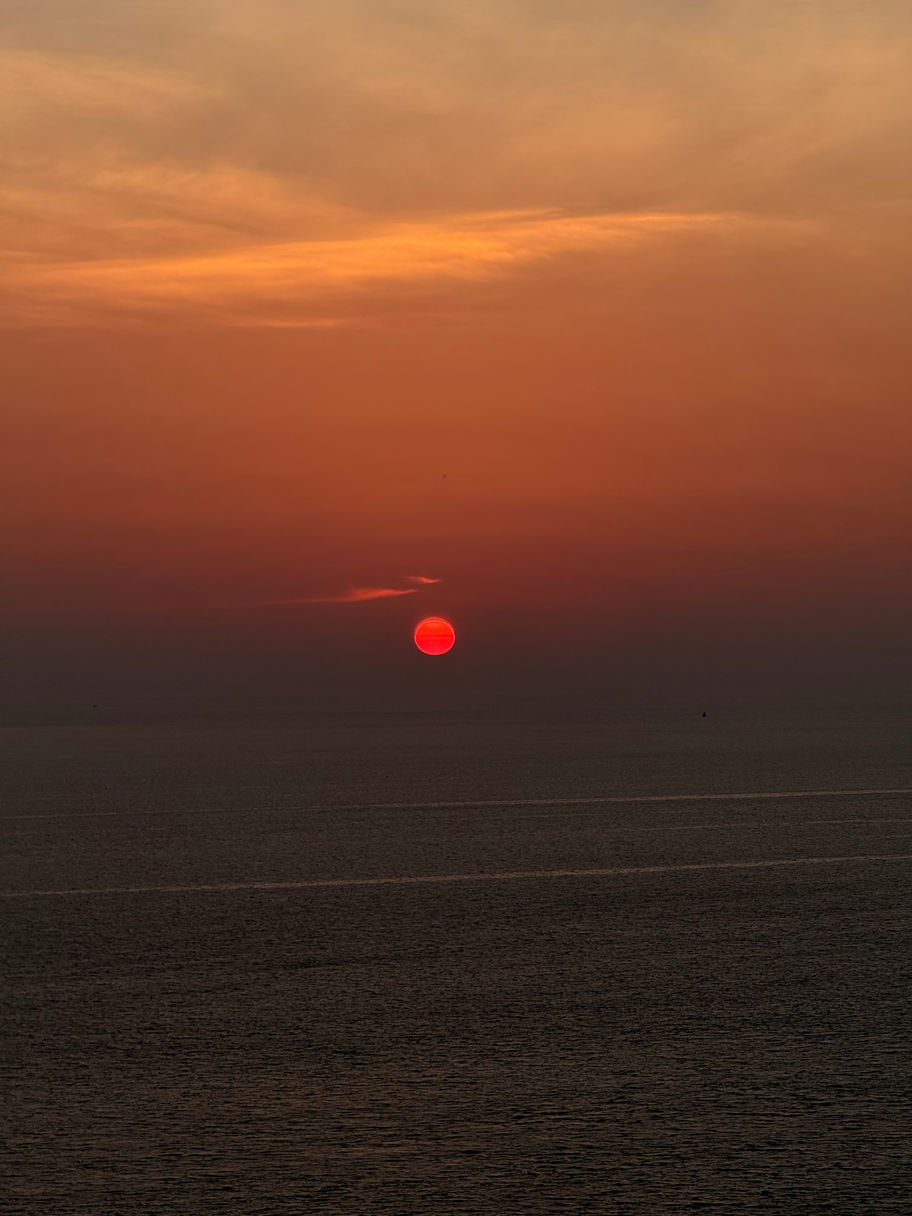red sun setting over the ocean at dusk