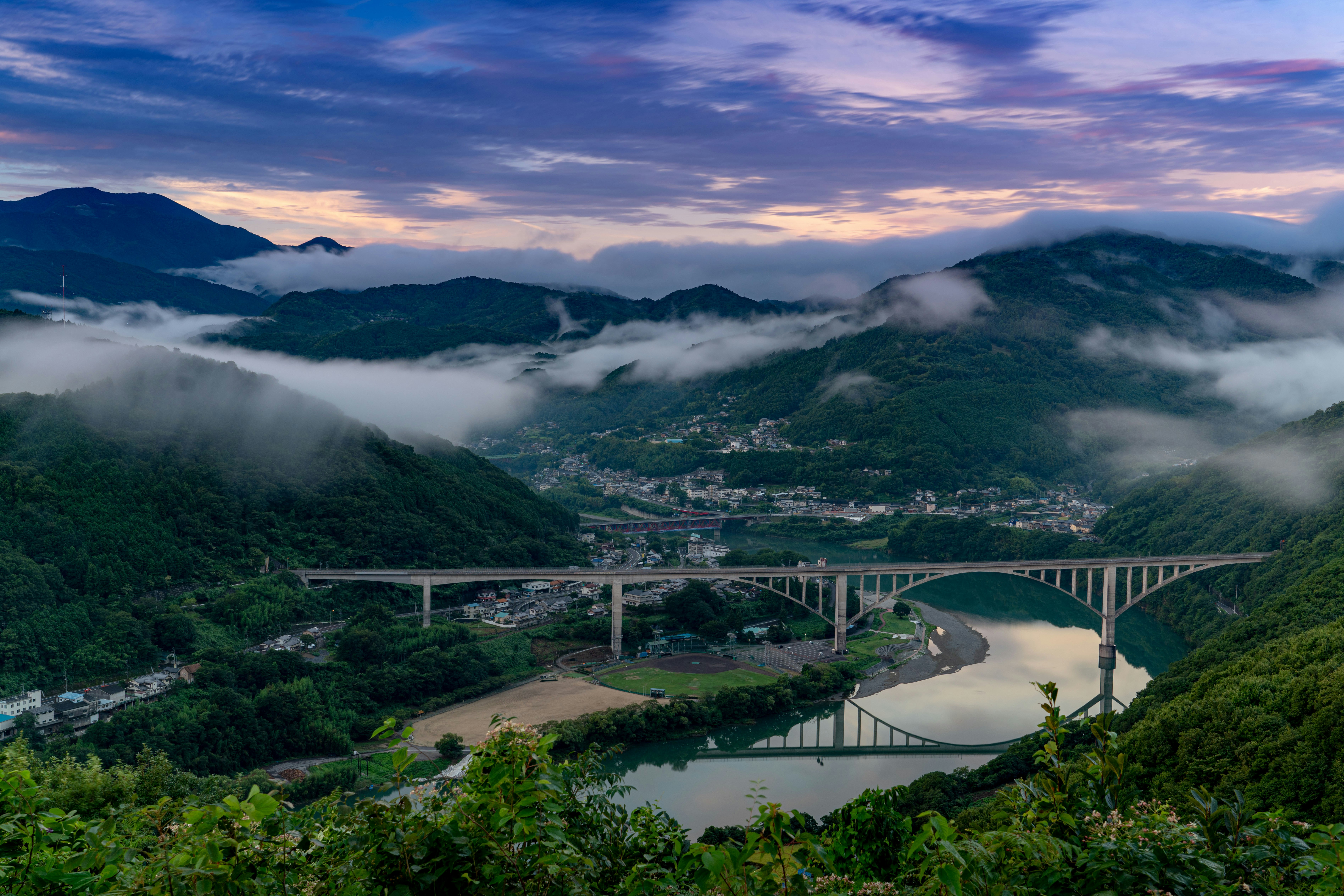 ทิวทัศน์หุบเขาเขาในหมอกพร้อมแม่น้ำและสะพาน