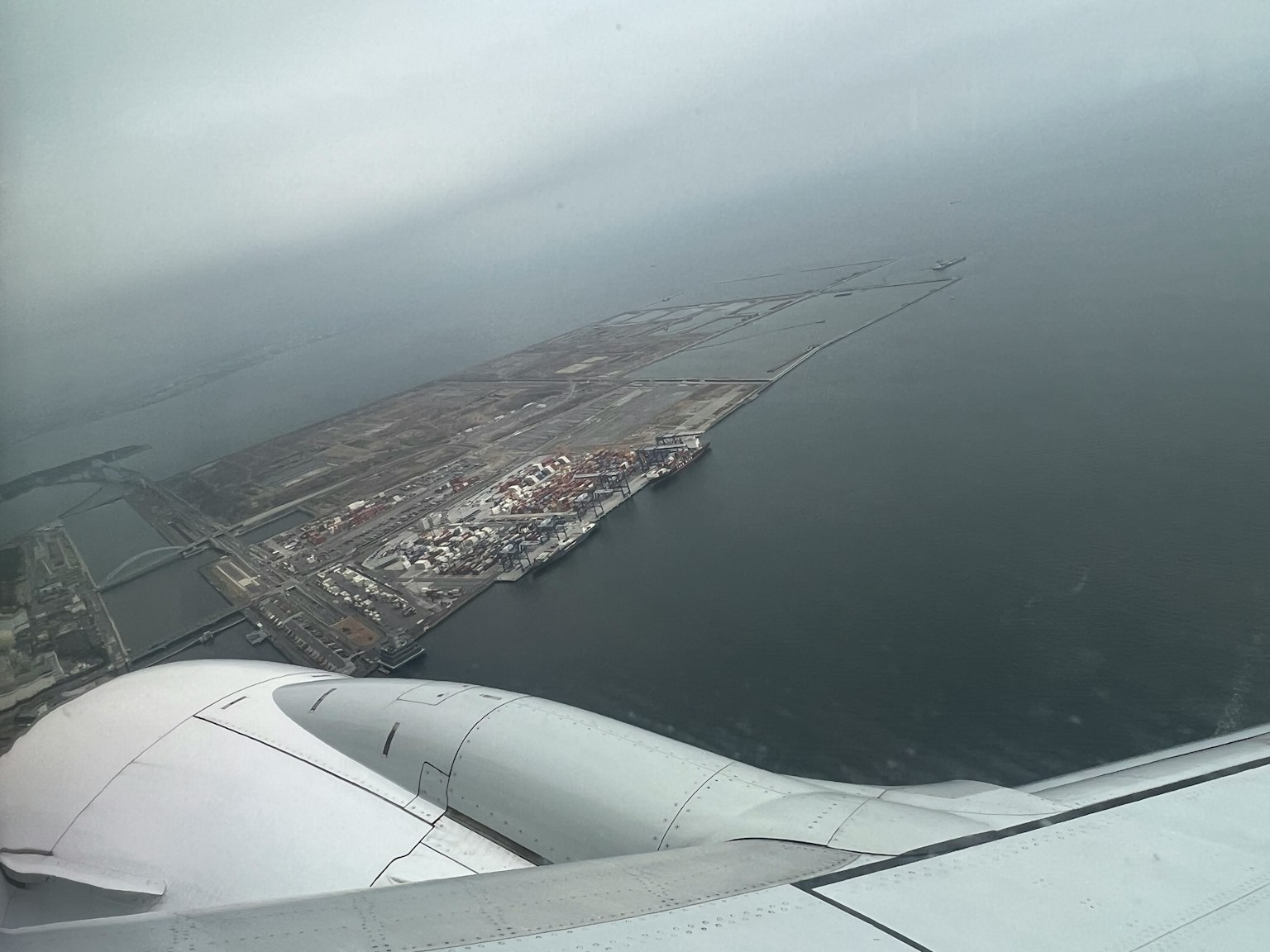 Vue aérienne d'une ville côtière avec une ligne de rivage visible depuis une fenêtre d'avion