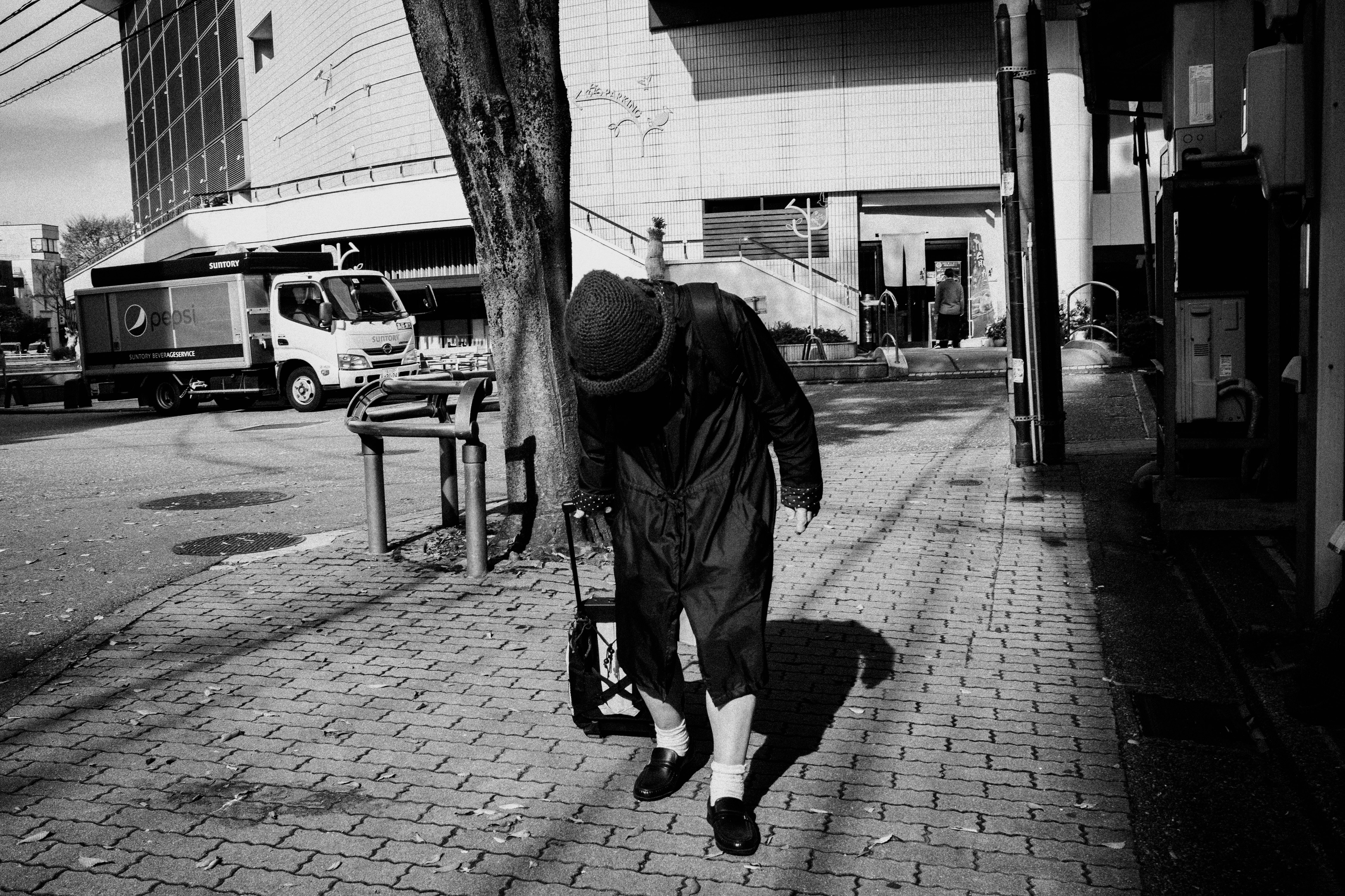 モノクロの老人が路地を歩く後ろ姿の街角