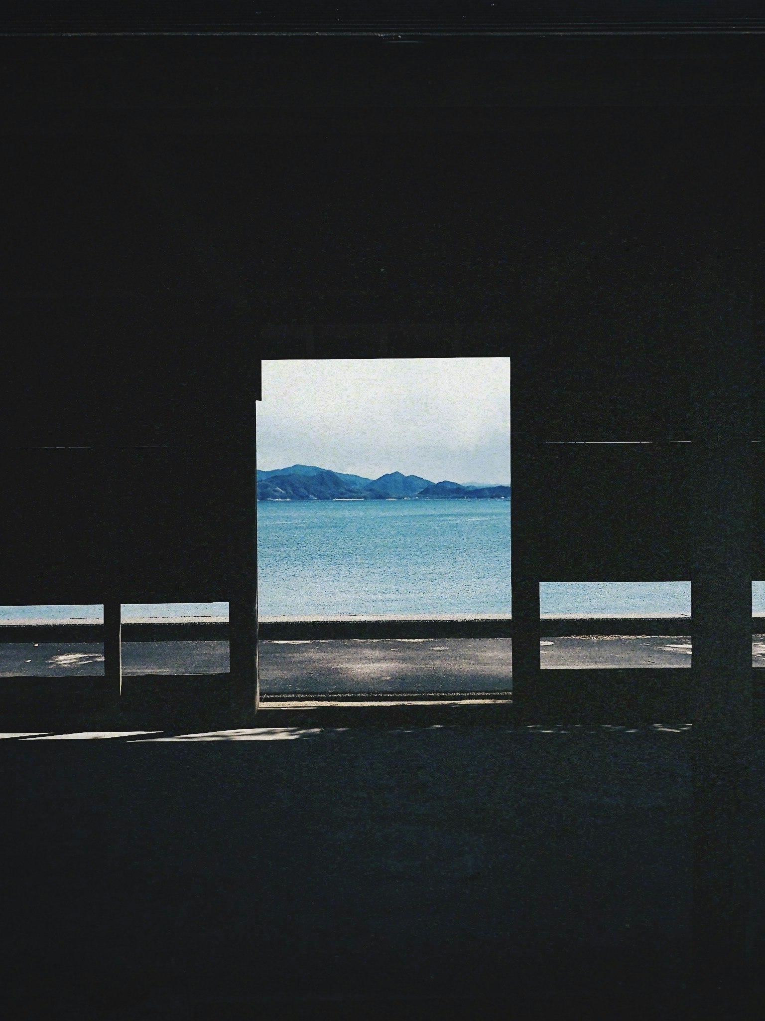 Blick auf das Meer und die Berge durch ein dunkles Fenster