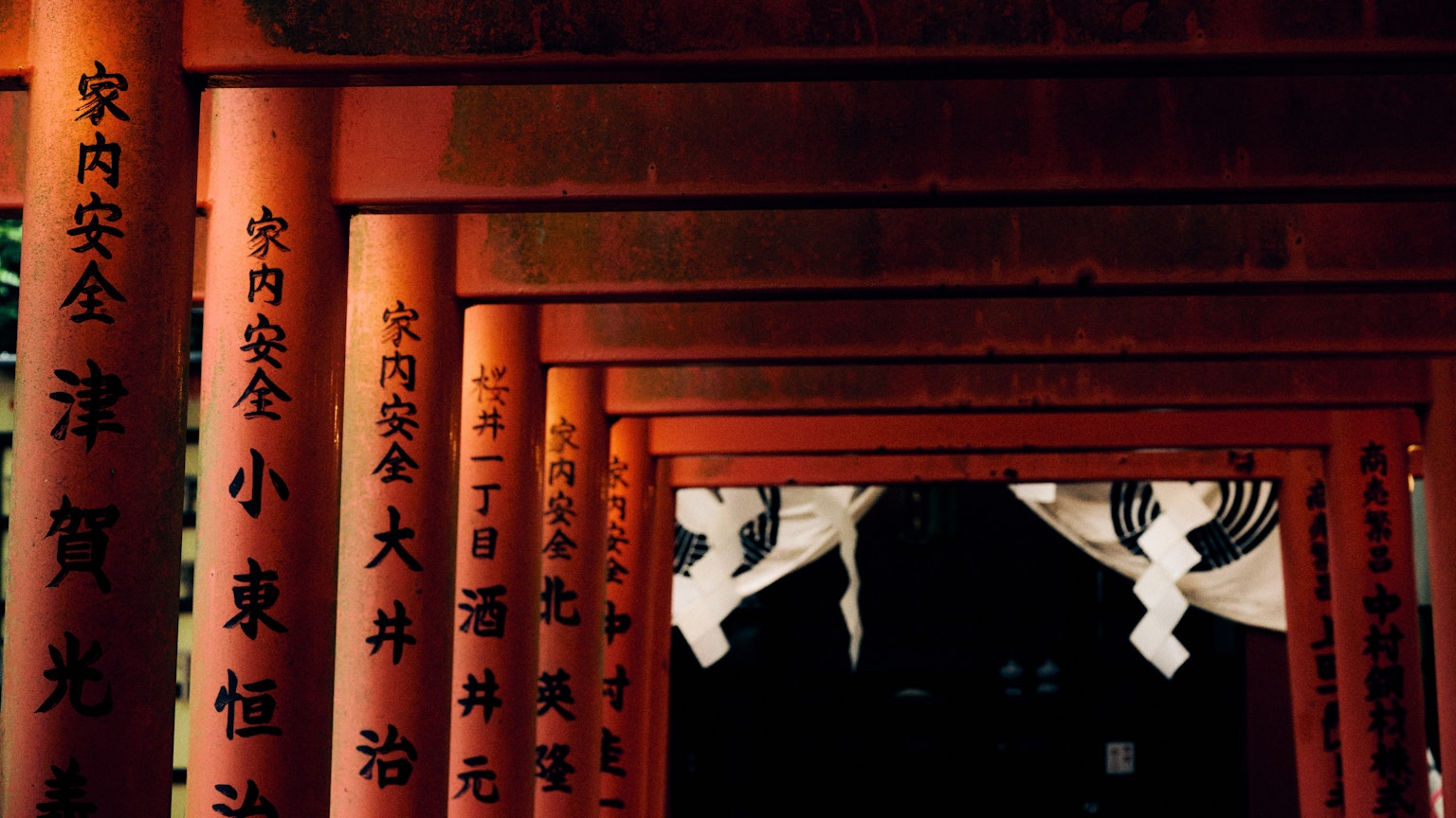 Tunnel aus roten Torii-Toren mit Kanji-Inschriften