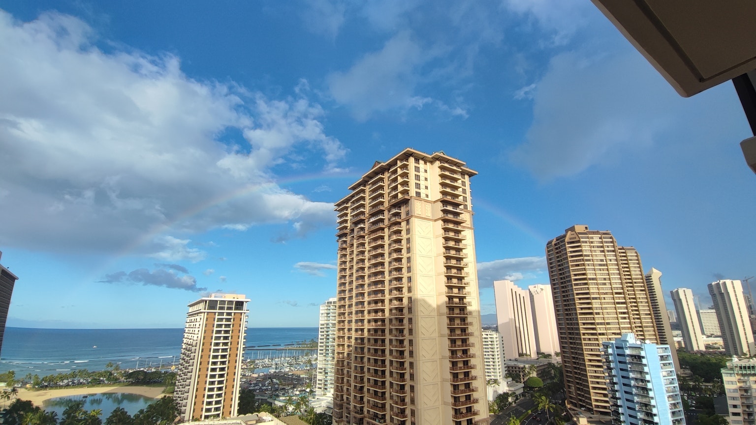 Vista del horizonte con edificios altos y océano bajo un cielo azul con nubes
