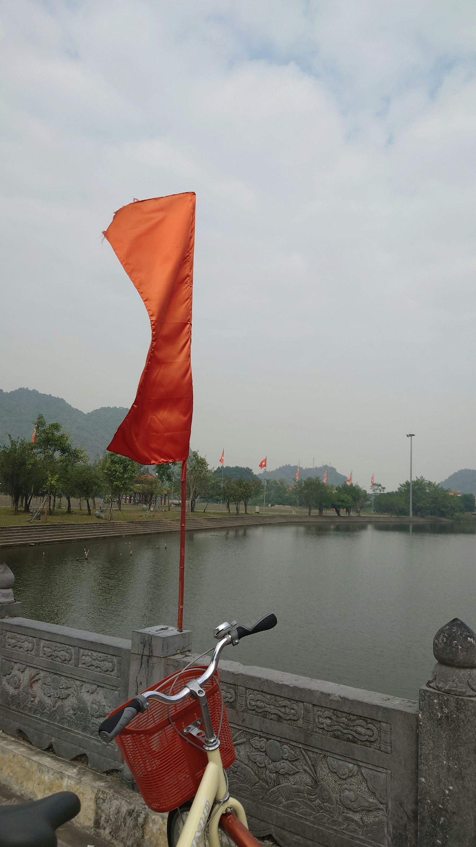 Paysage avec un drapeau orange près d'un étang et un vélo au premier plan