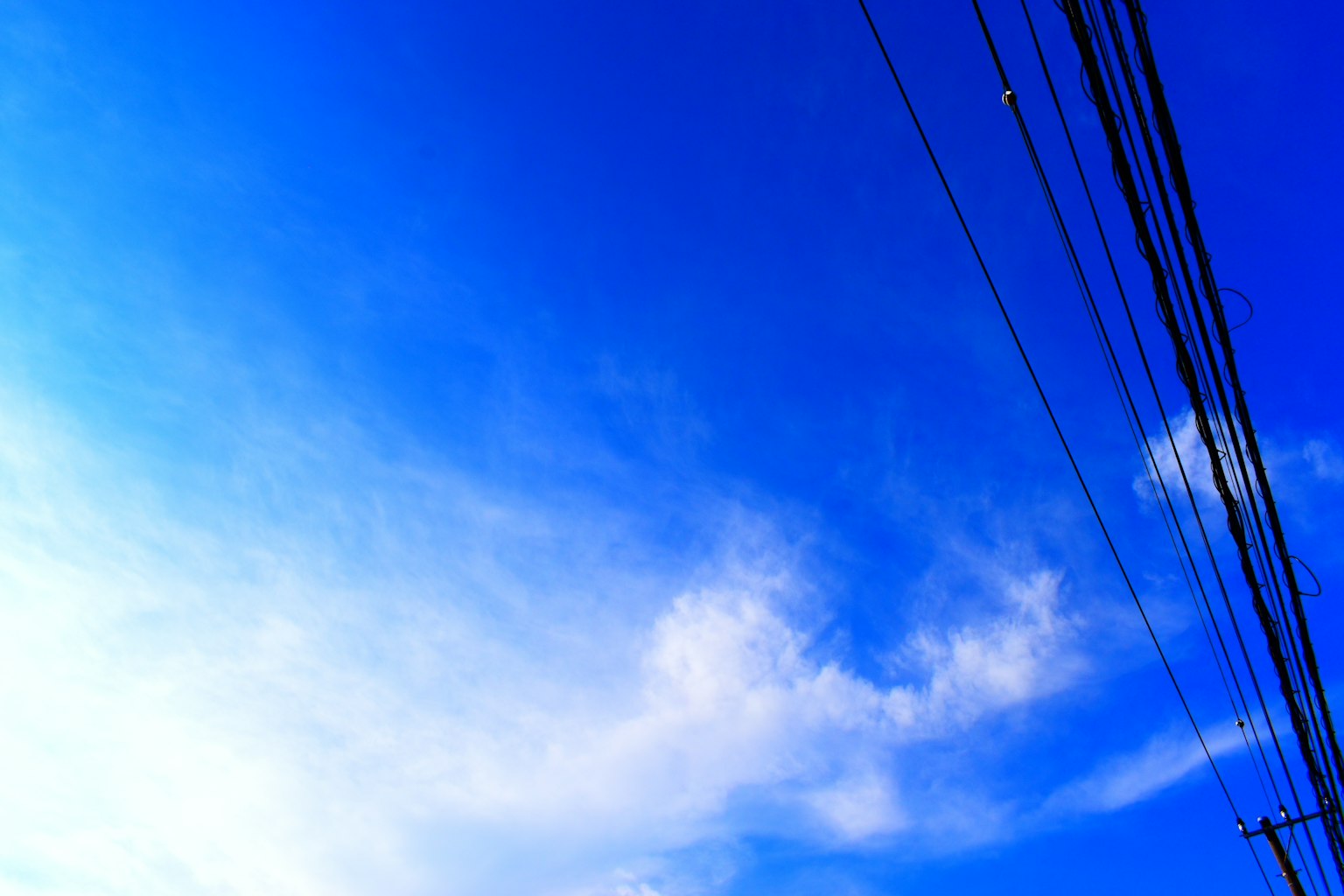 Foto langit biru dengan awan dan saluran listrik yang terlihat