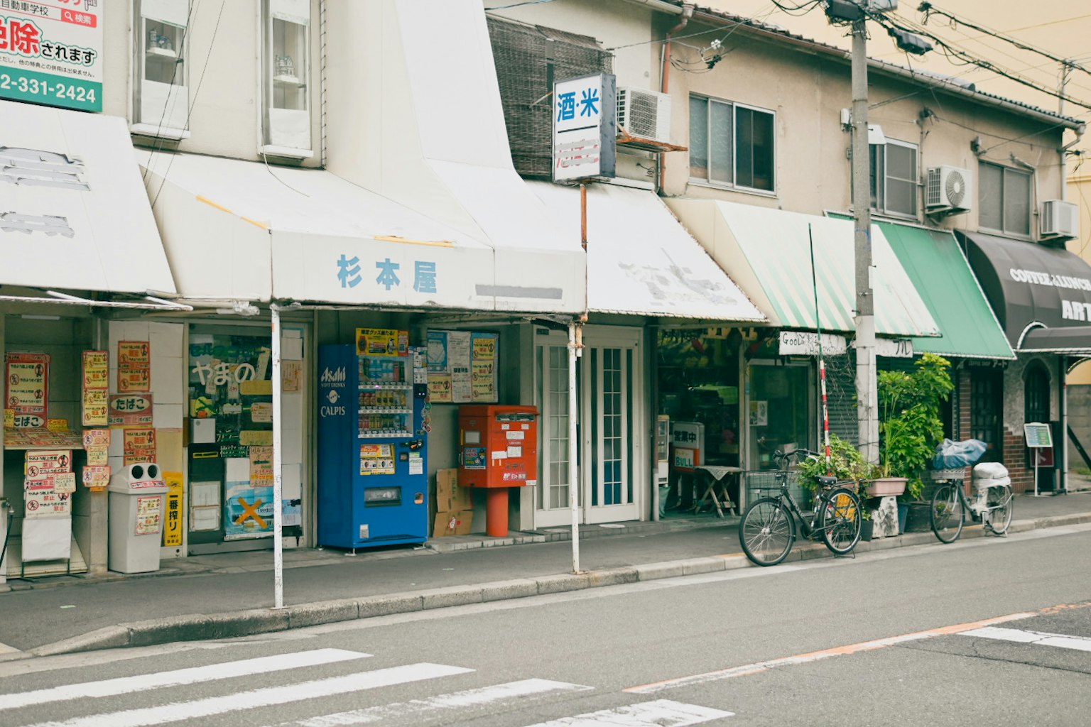 Straßenszene mit Geschäften, die einen Automaten und einen Briefkasten zeigen