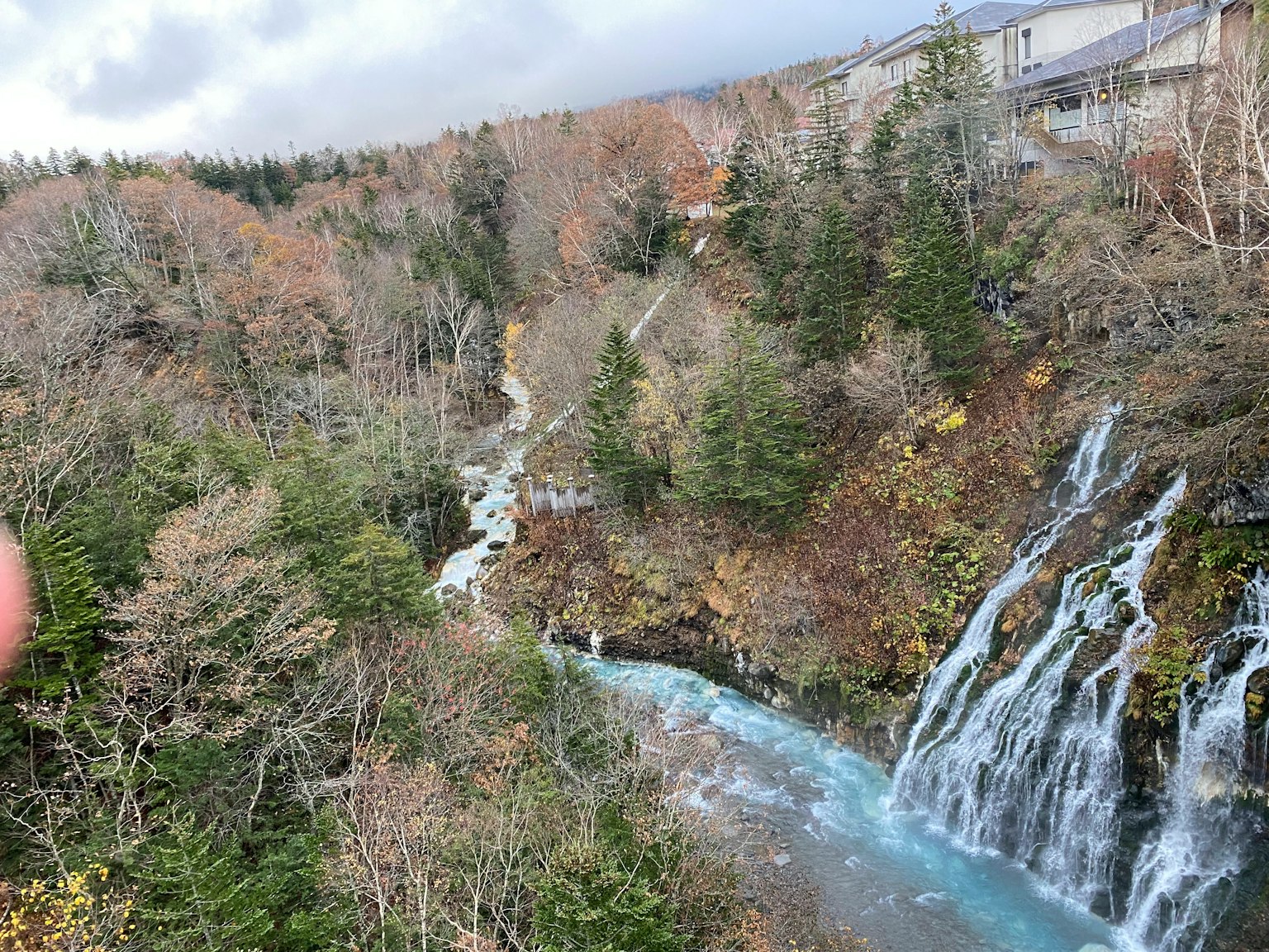 Vista escénica de una cascada y un río azul con follaje otoñal y árboles circundantes