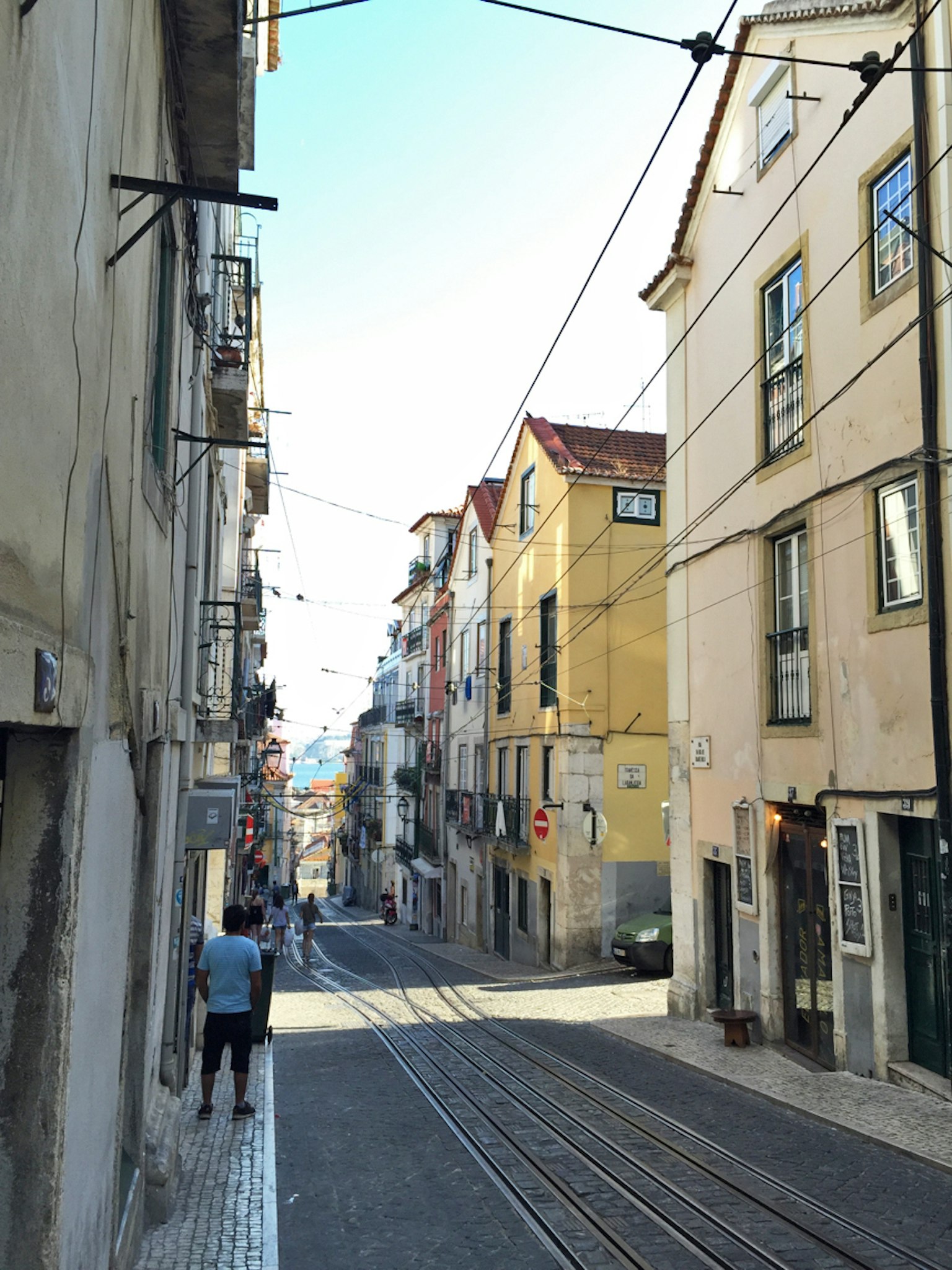 Narrow street in Lisbon with colorful buildings and tram tracks