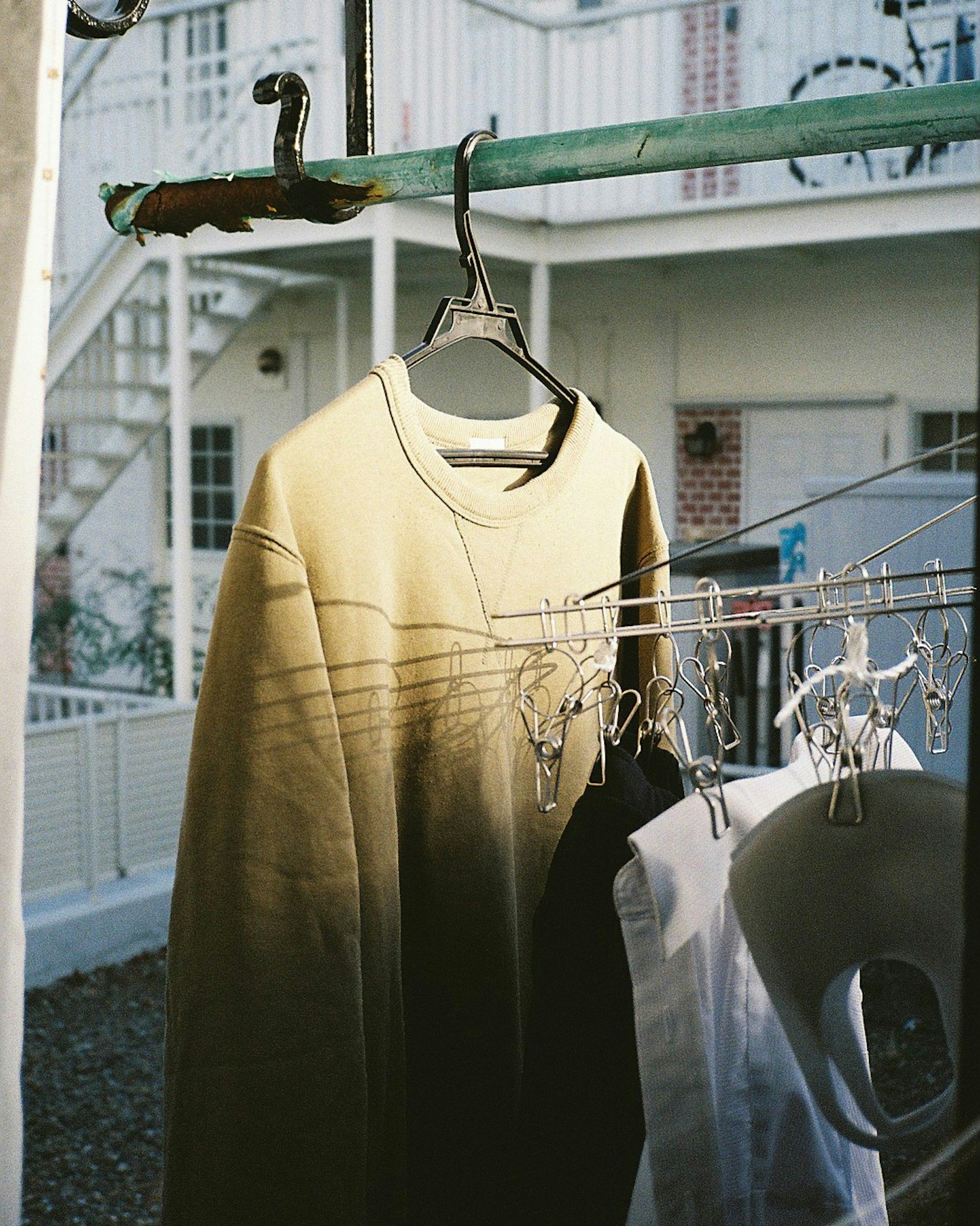 A scene of laundry drying with an olive green sweatshirt hanging on a hanger