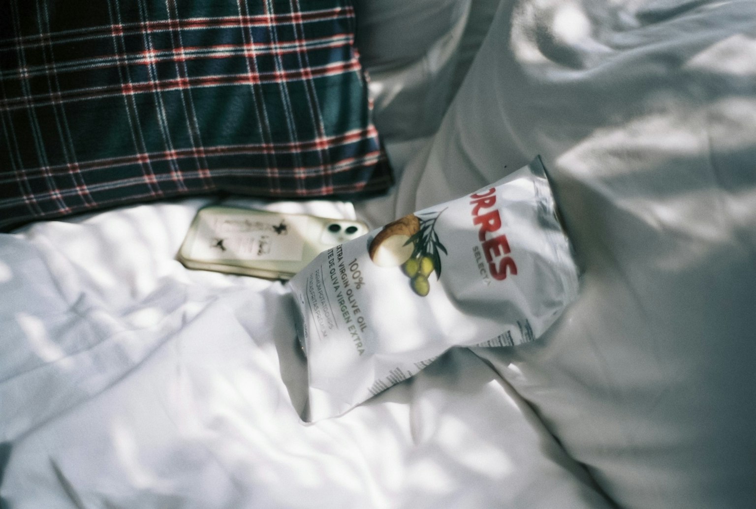 Gambar paket camilan dan smartphone di atas seprai putih