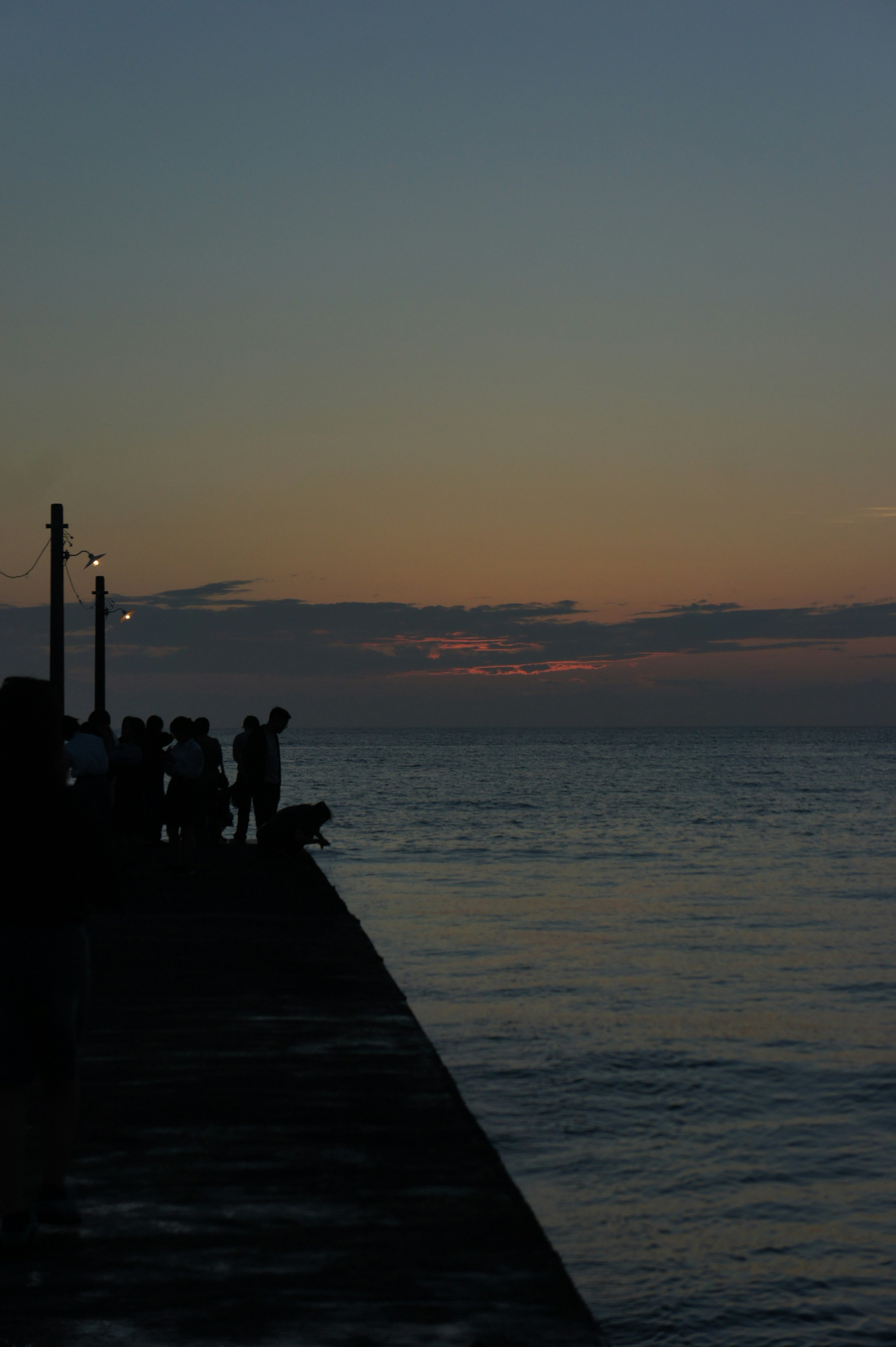 persone in silhouette su un molo al tramonto