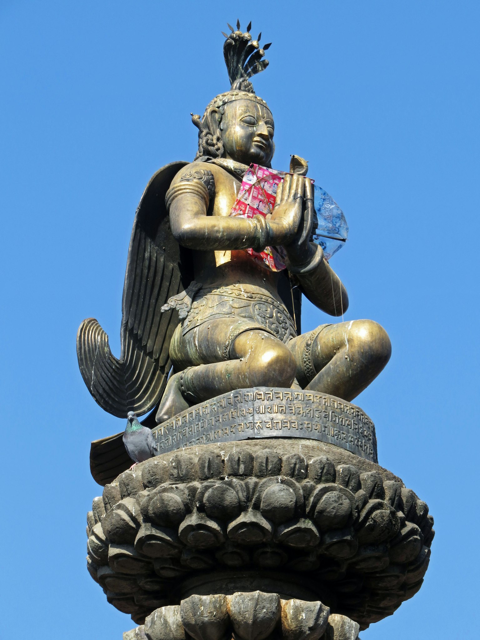 Statua di una divinità in posa di preghiera contro un cielo blu