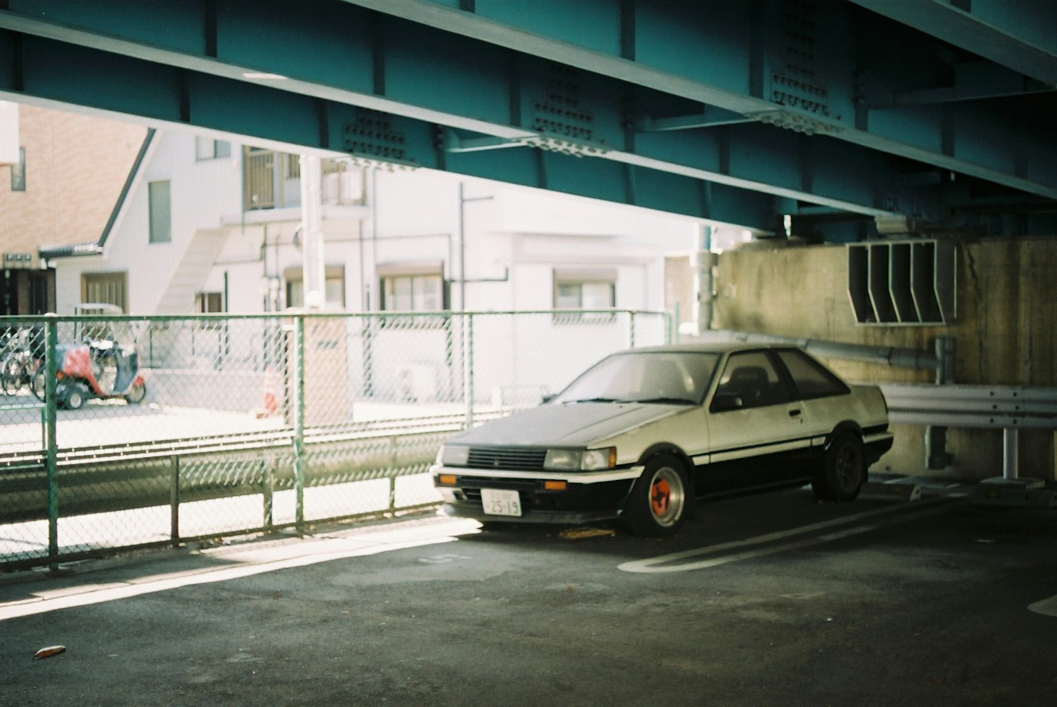 一輛舊車停在屋頂下的停車場背景中可見建築